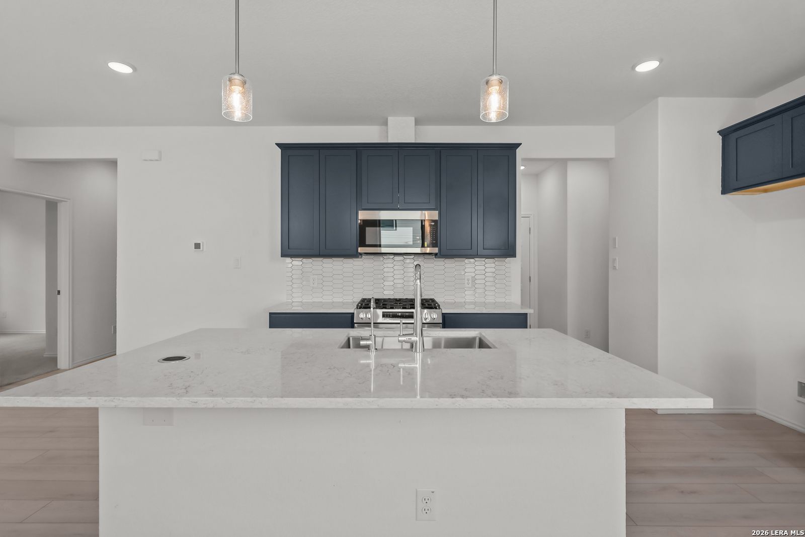Modern kitchen with navy cabinets, quartz island, and pendant lighting in The Gillian C floor plan, Meadows at Oak Creek.