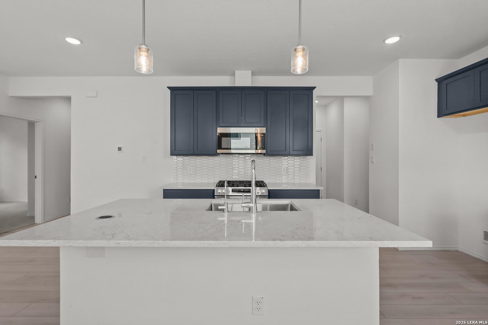 Modern kitchen with navy cabinets, quartz island, and pendant lighting in The Gillian C floor plan, Meadows at Oak Creek.