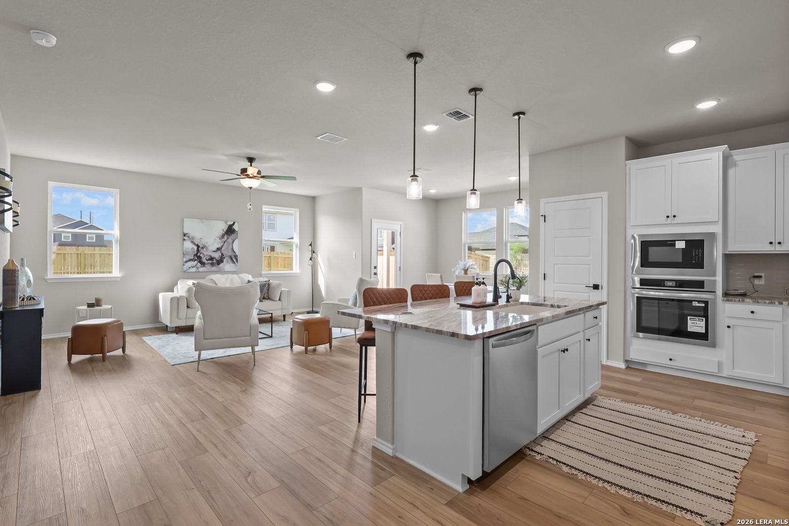 Open-concept kitchen and living area with island, white cabinetry, and hardwood floors in The Daphne H plan, Hannah Heights, Seguin