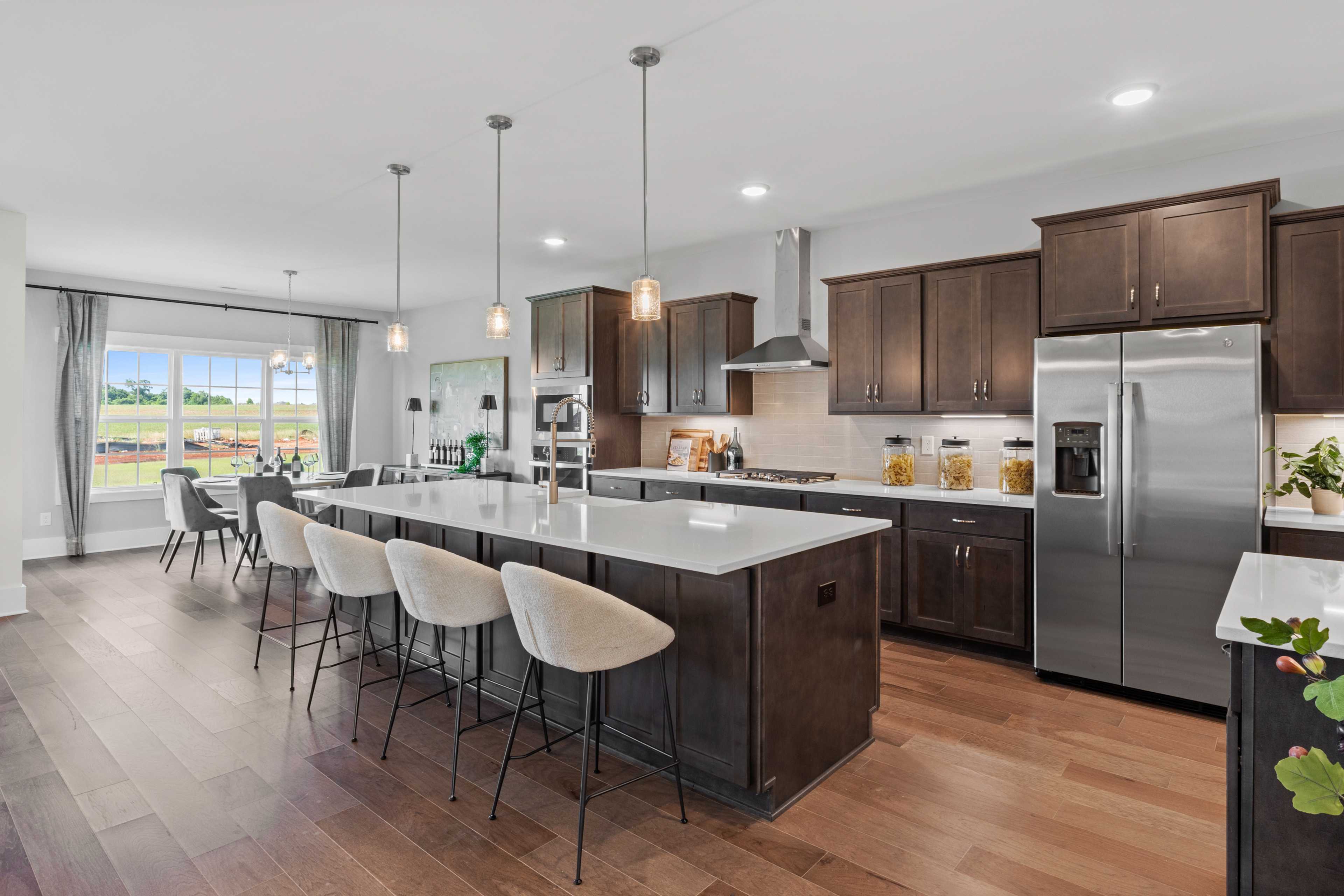Spacious open-concept kitchen in Creekside Harvest AL with quartz island, dark cabinets, stainless appliances, hardwood floors