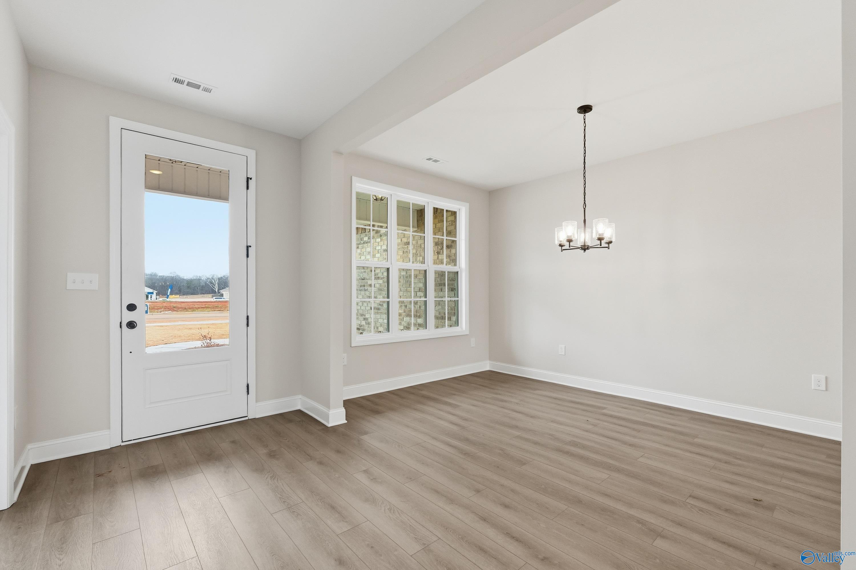 Elegant dining room with crystal chandelier, large window, and open door to yard in Davidson Homes The Finleigh, Meridianville, AL