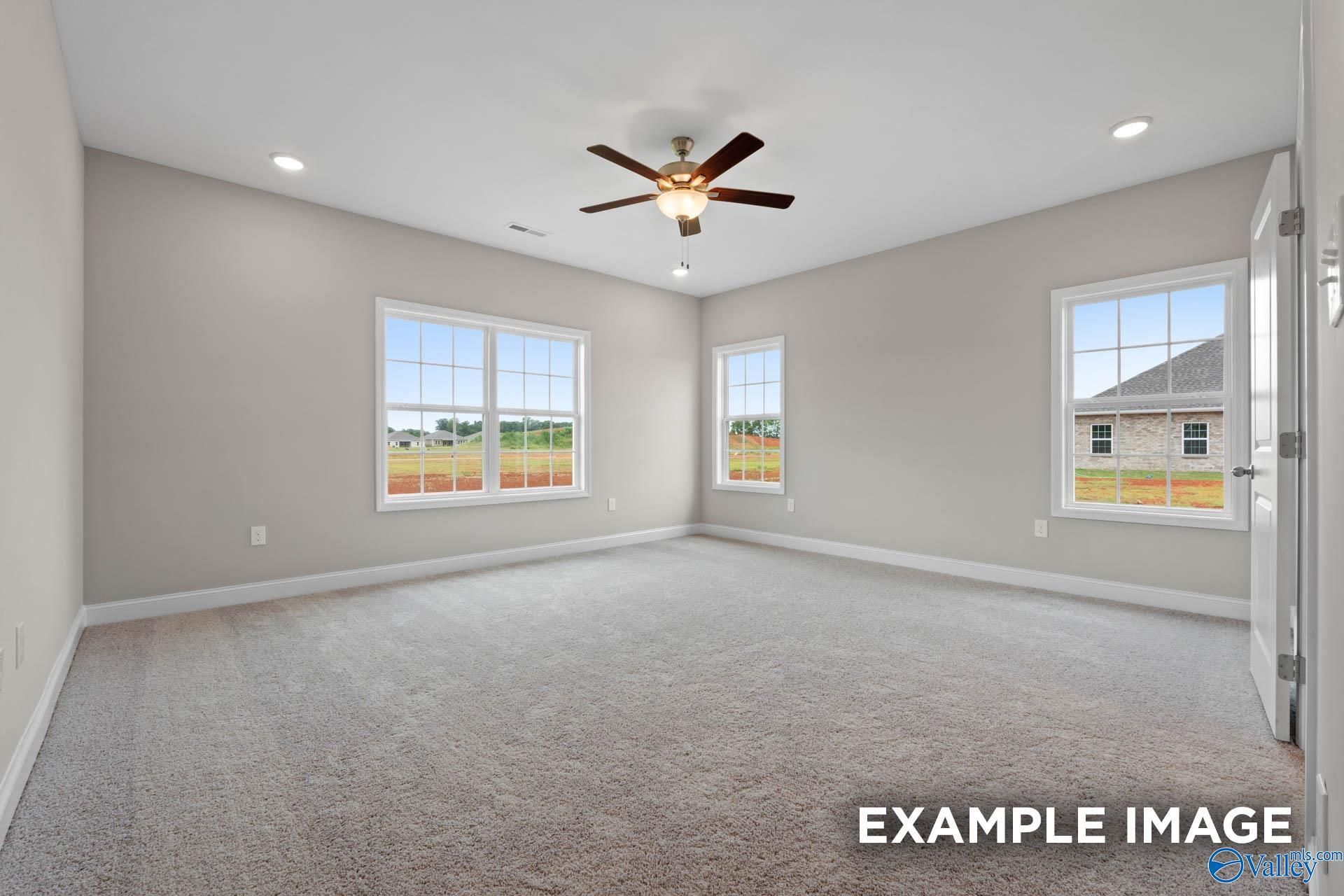 Spacious living room with large windows overlooking fields, ceiling fan, and neutral gray walls in Davidson Homes The Finleigh, Creekside, Harvest, Alabama
