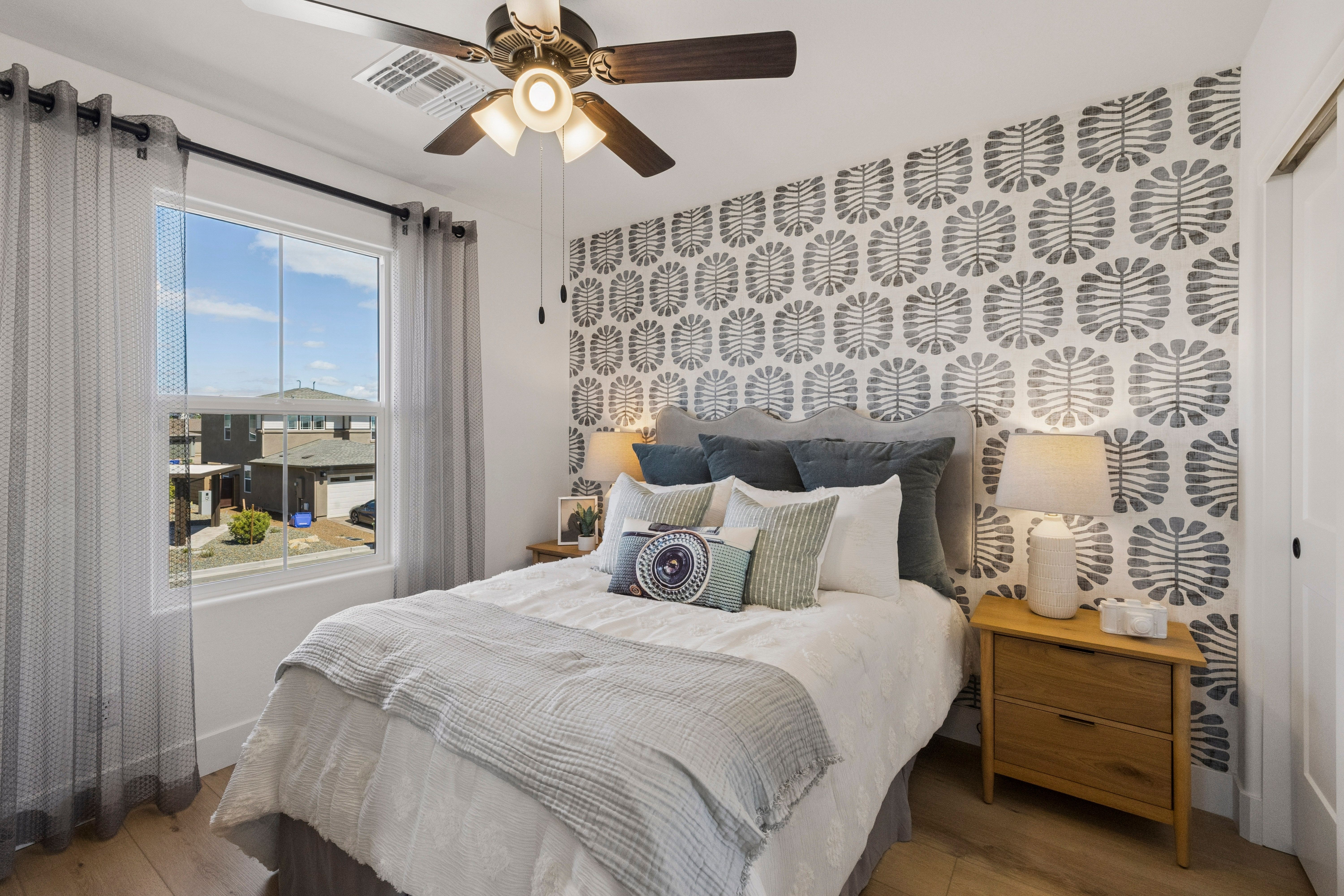 Cozy bedroom at South Ranch Southern Collection in Prescott AZ with gray patterned accent wall, king bed, sheer curtains, and desert view