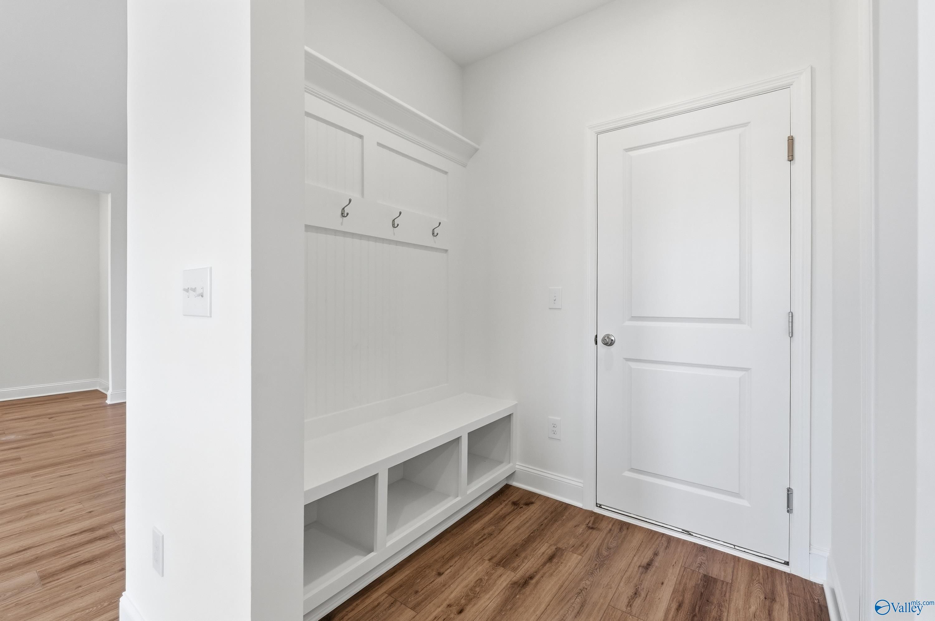 White mudroom with built-in bench, coat hooks, and storage cubbies in Davidson Homes The Montgomery C, Harvest AL