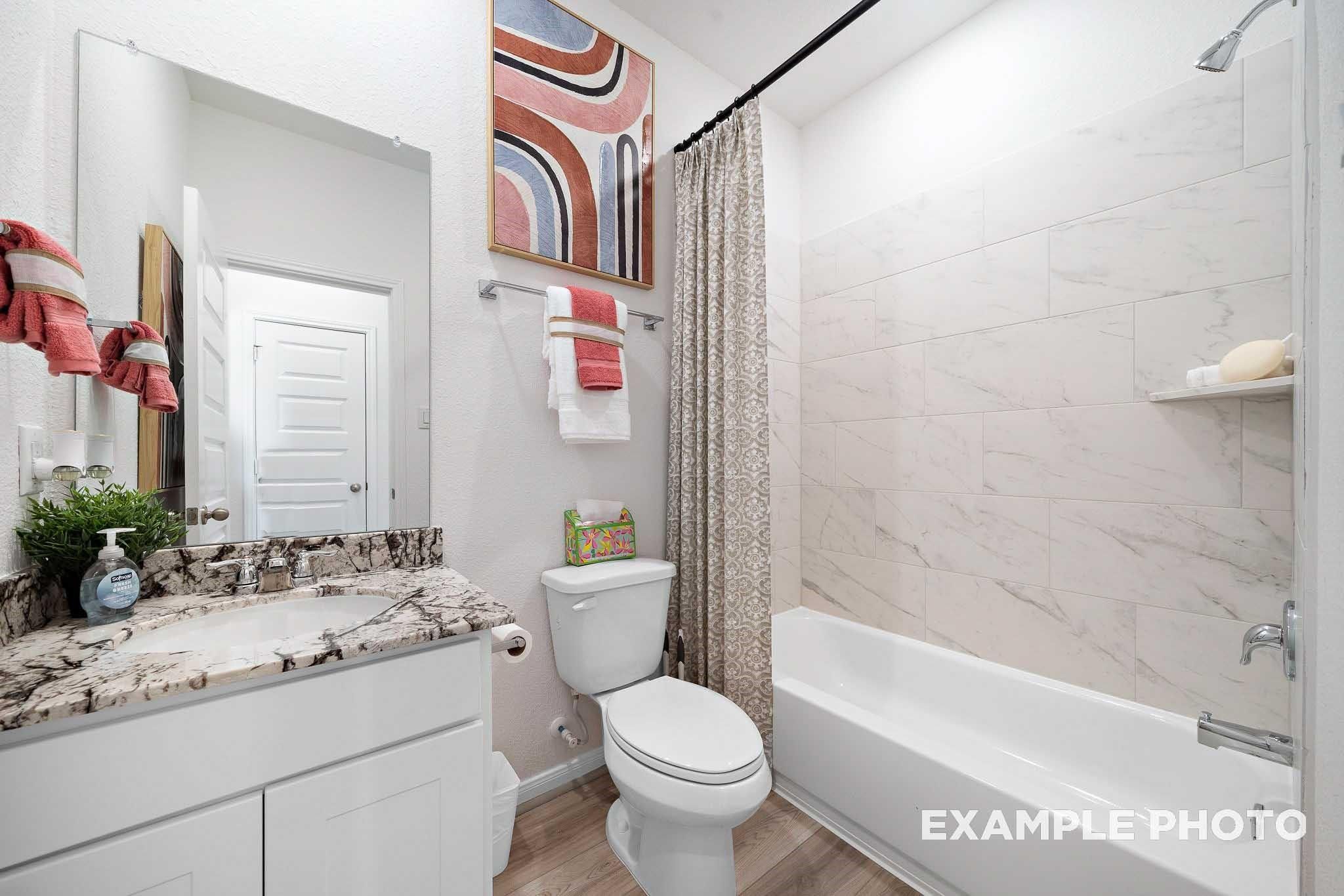 Modern bathroom featuring double vanity, soaking tub, subway tile, and abstract art in The Sabine F by Davidson Homes, Magnolia, Texas