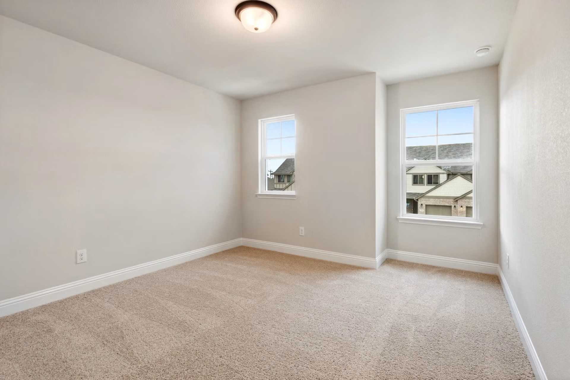 Bright secondary bedroom with beige carpet, light gray walls, and large windows overlooking neighborhood in The Wake D, Wylie, Texas