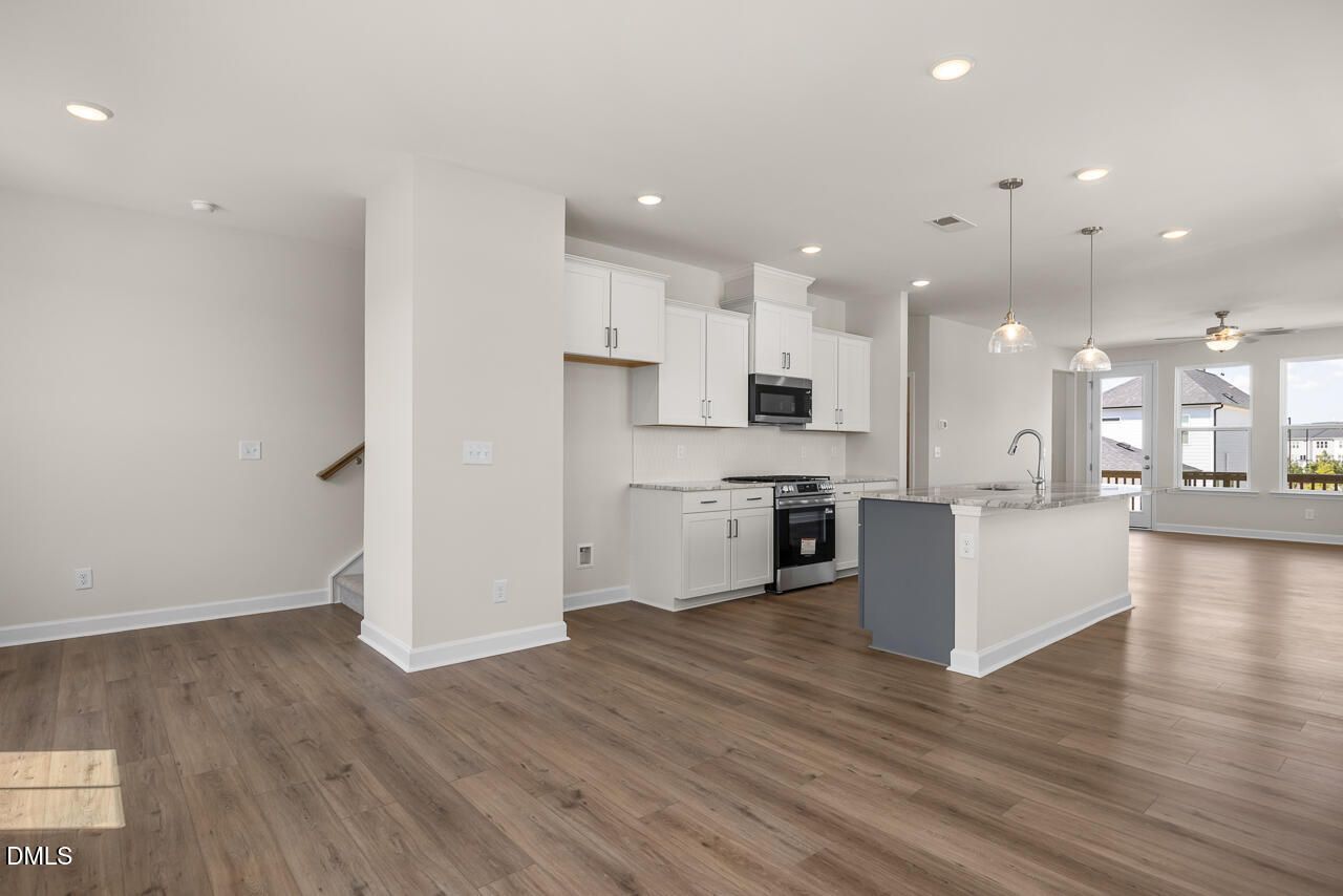 Open-concept kitchen with white cabinetry, gray island, and luxury vinyl plank flooring in Davidson Homes townhome, Knightdale NC