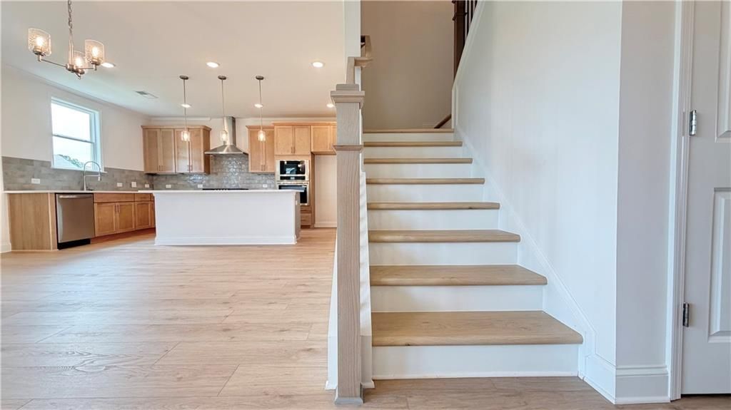 Open-concept kitchen and staircase in The Hickory C floor plan at Wehunt Meadows, Hoschton, Georgia.
