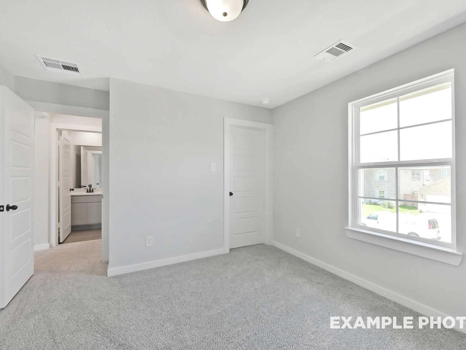 Bright bedroom with plush carpet and en-suite bathroom in The Sequoia C floor plan at Sundance Cove, Crosby, Texas.