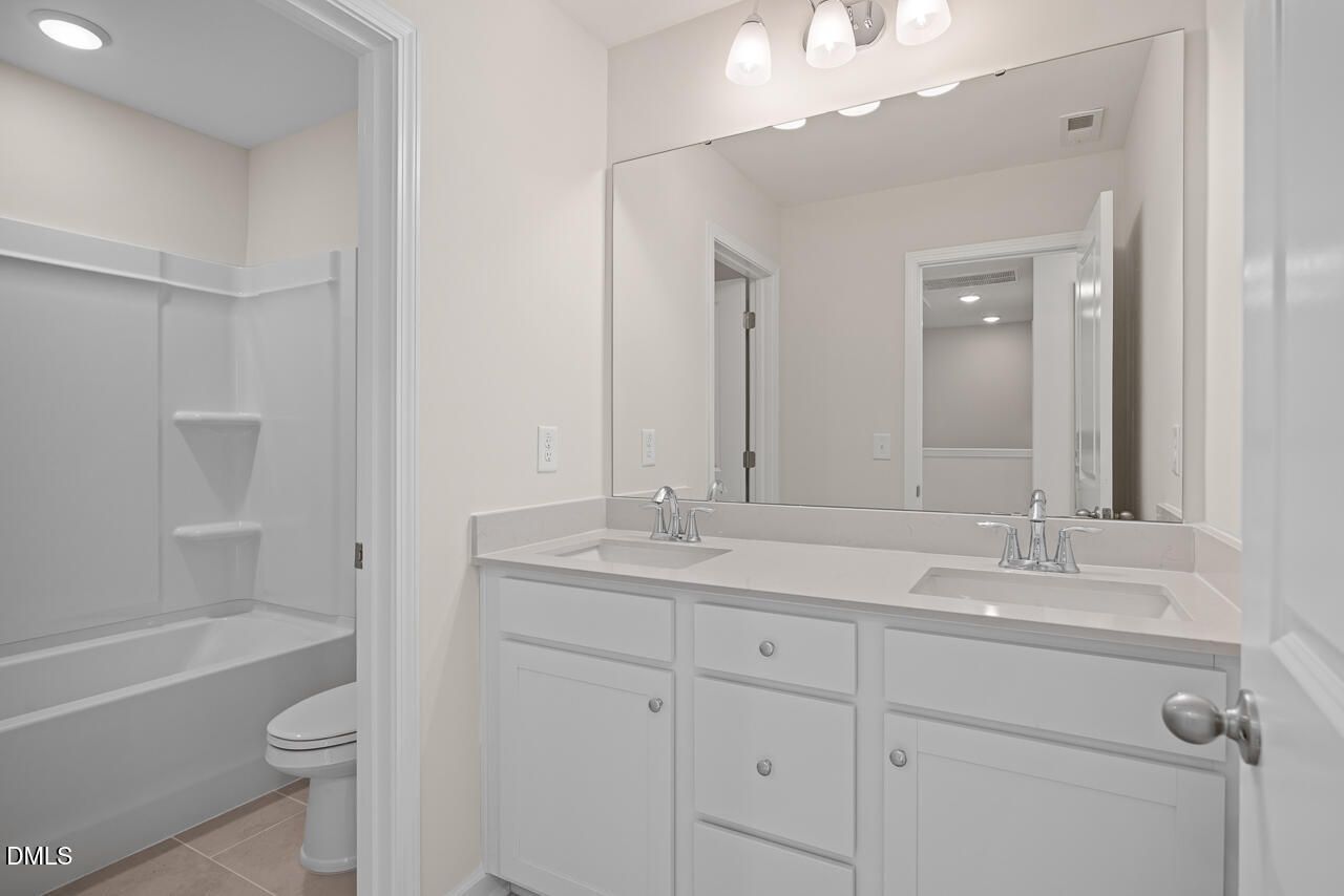 Double vanity bathroom with white cabinetry and tub shower in The Mitchell floor plan at Forestville Yard Townhomes, Knightdale, NC