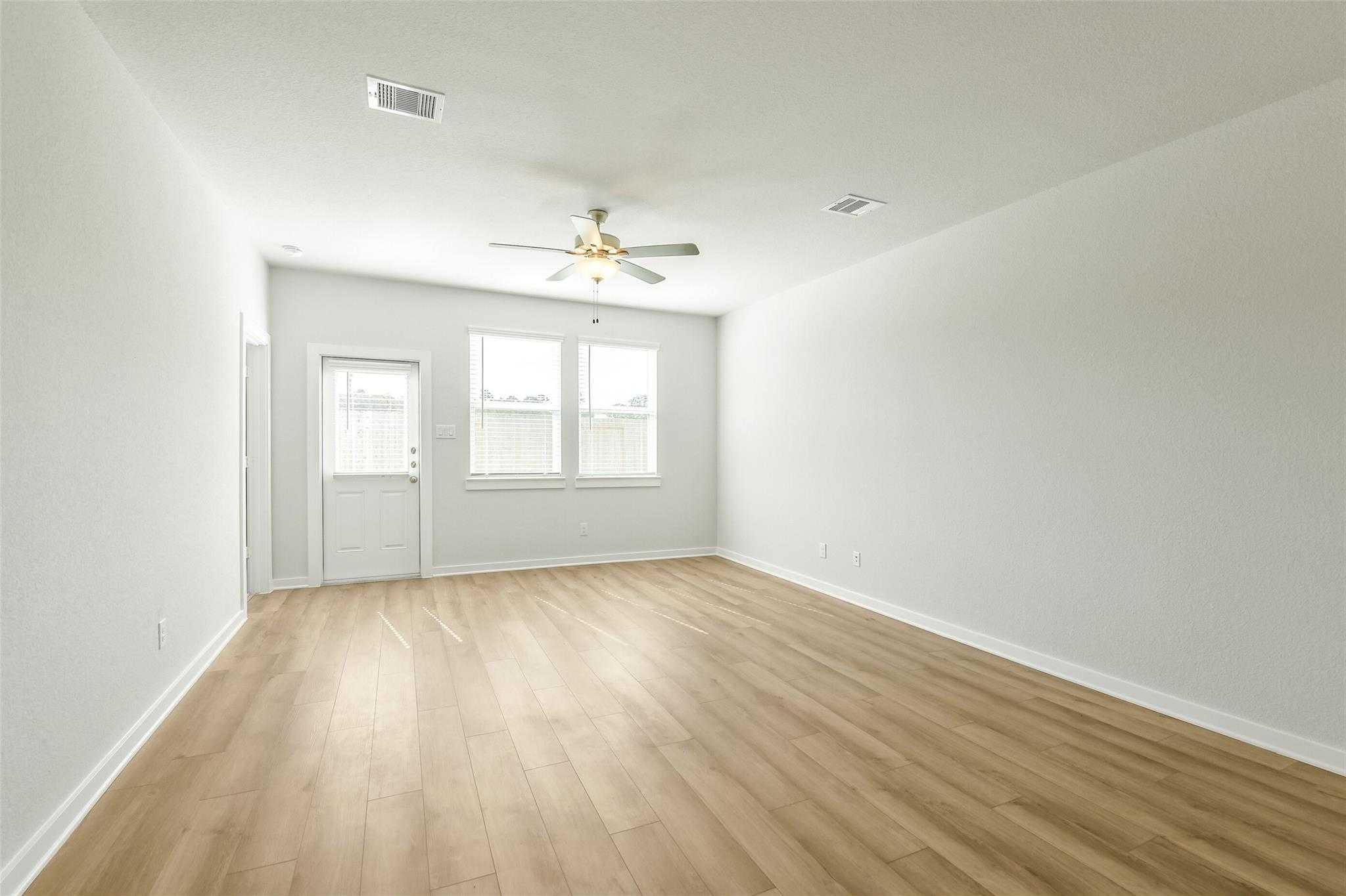 Spacious empty upstairs room with light hardwood floors, white walls, ceiling fan, and large windows in Davidson Homes San Marcos E, Cleveland, Texas