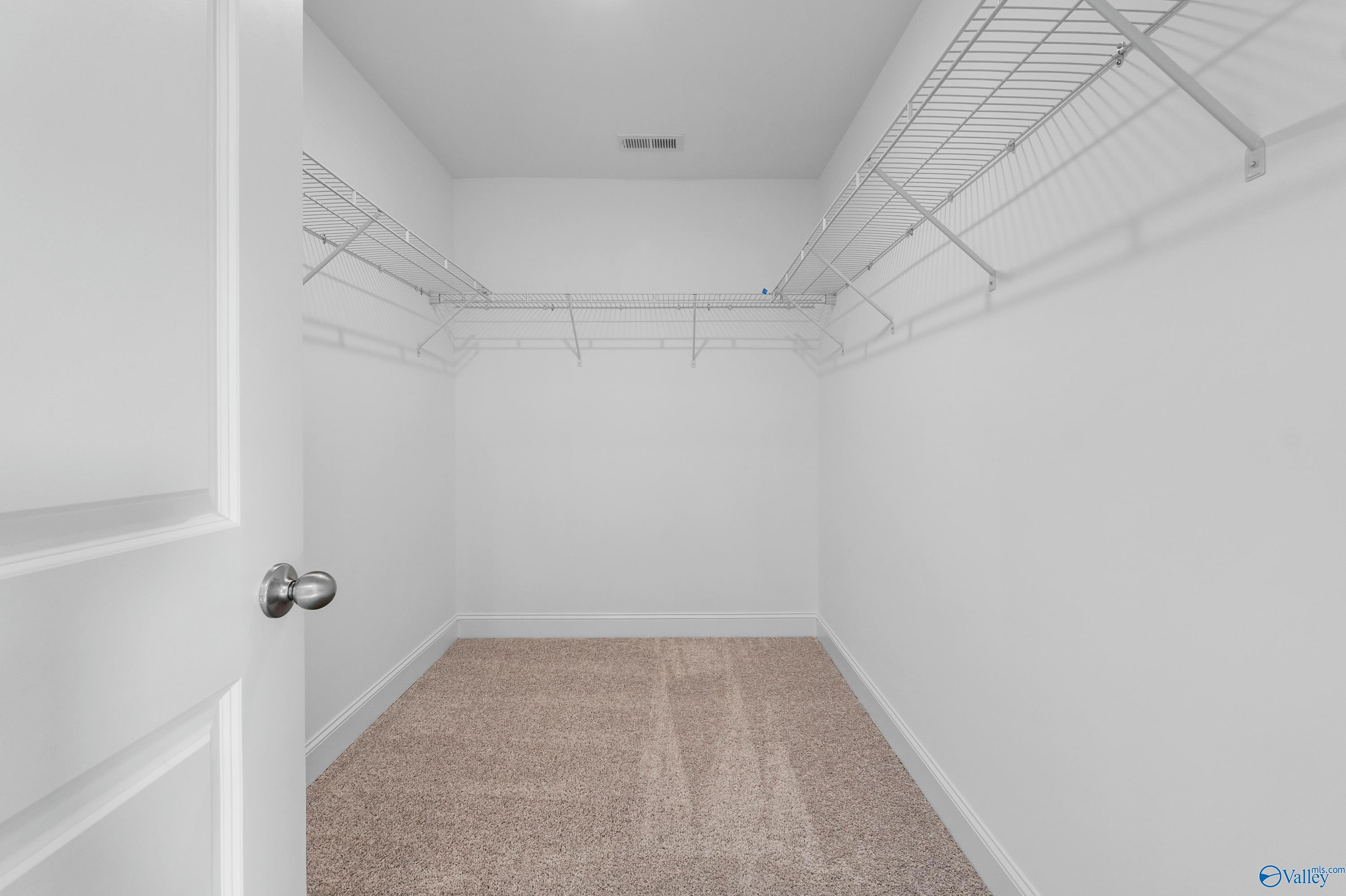Spacious walk-in closet with wire shelving and beige carpet in Davidson Homes The Camden, Pavilion, Huntsville, Alabama