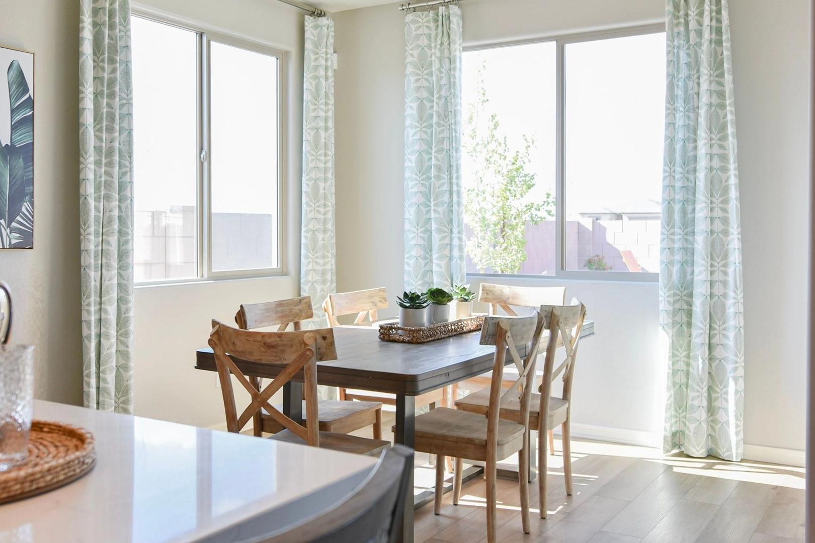 Spacious dining area in The Harmony B featuring wooden table with chairs, large windows, and natural light in Prescott Valley home