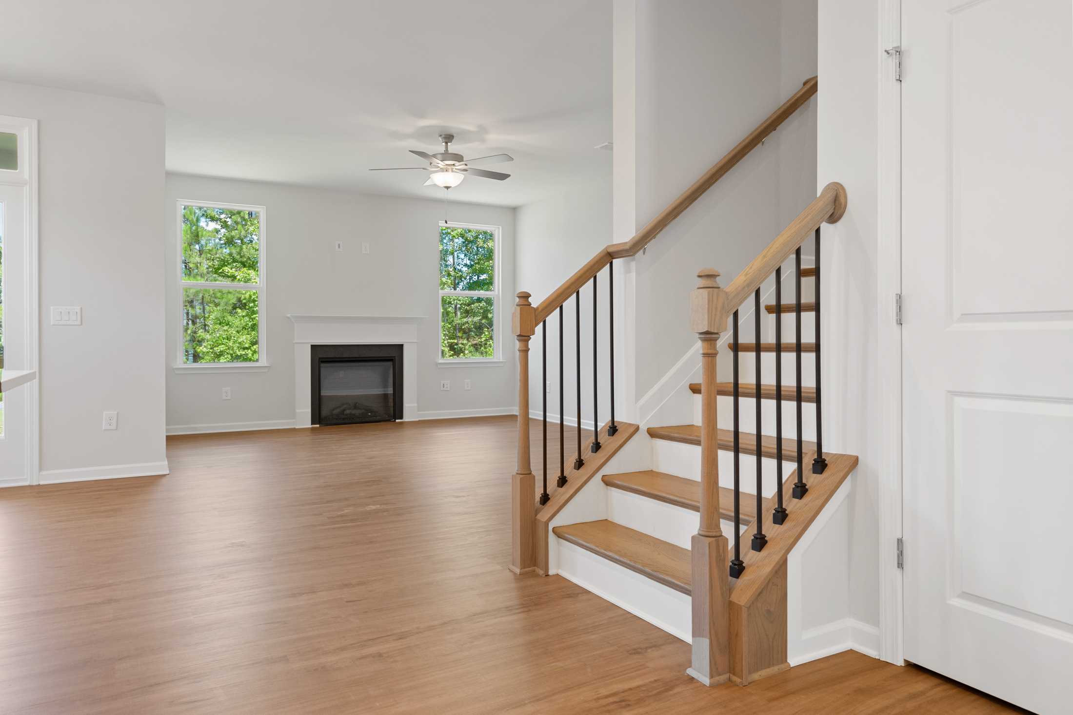 Spacious open-concept living area in Mountainbrook Cartersville GA with hardwood floors, gas fireplace, large windows, and wooden staircase