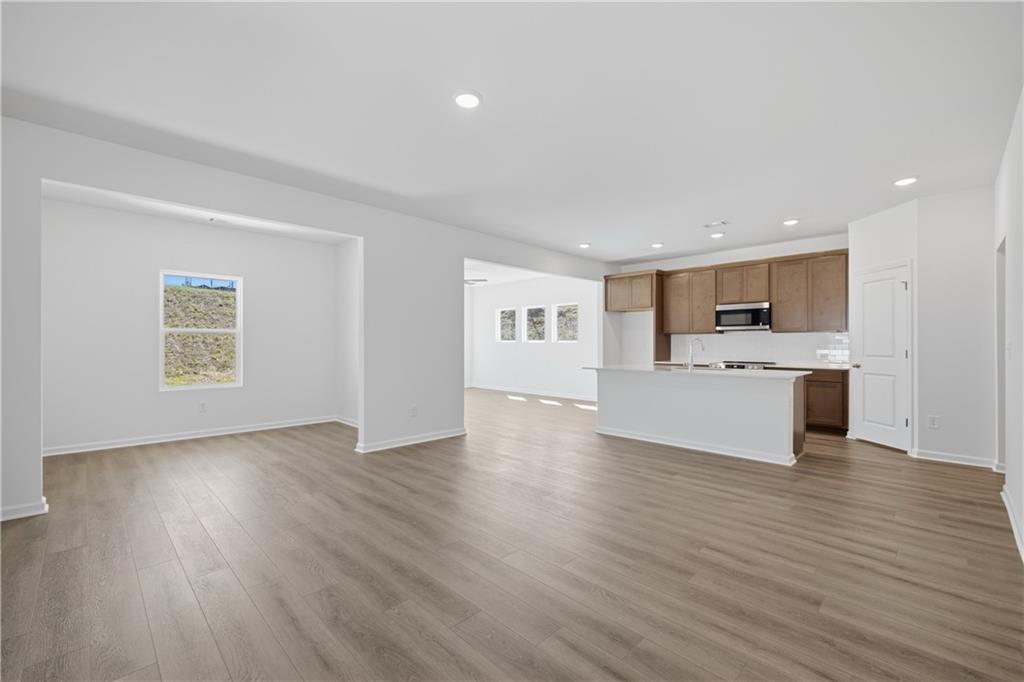 Open-concept living area with kitchen island and wood-look flooring in Davidson Homes The Russell B, Canton, Georgia