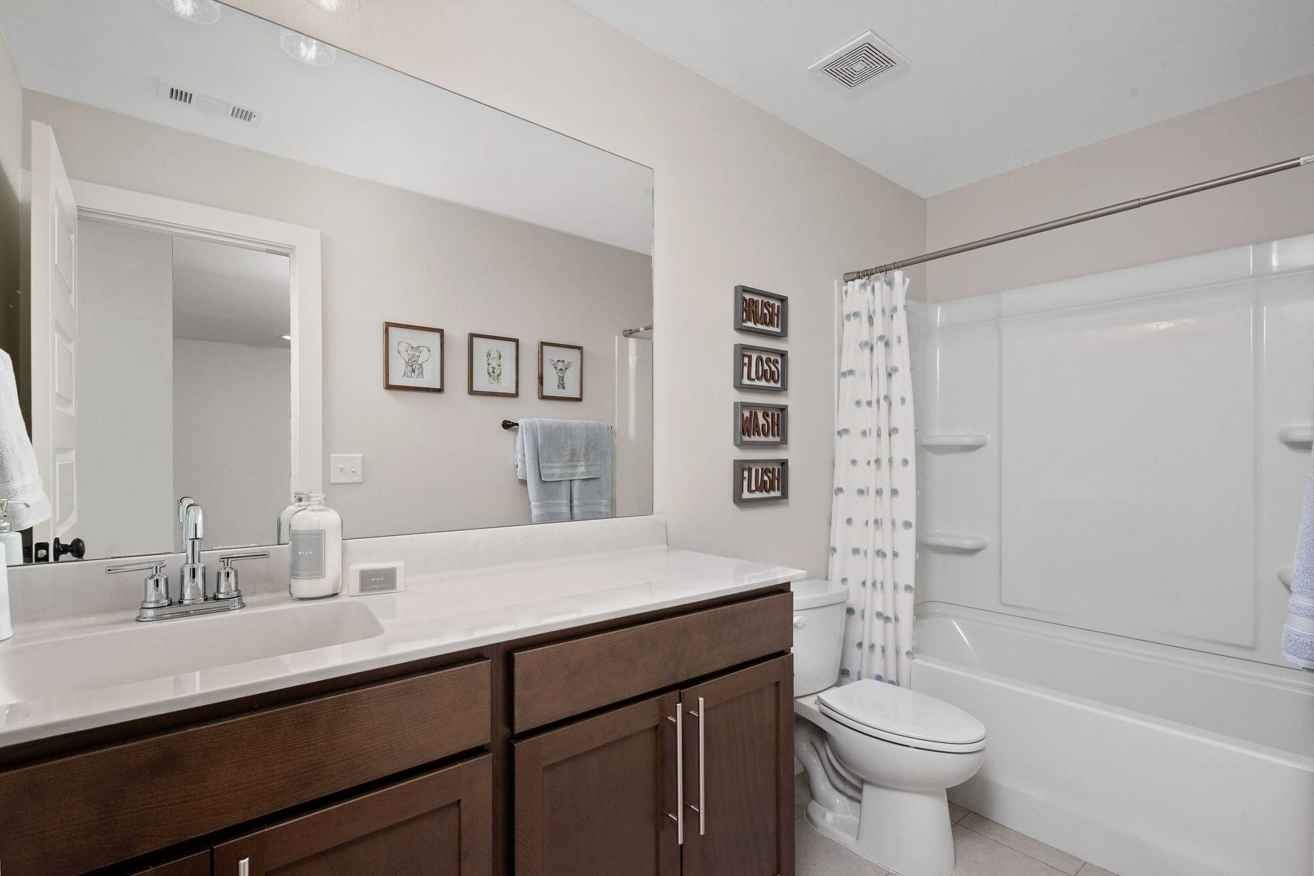 Modern bathroom at Rivers Edge in Murfreesboro TN with white bathtub, dark wood vanity, and large mirror