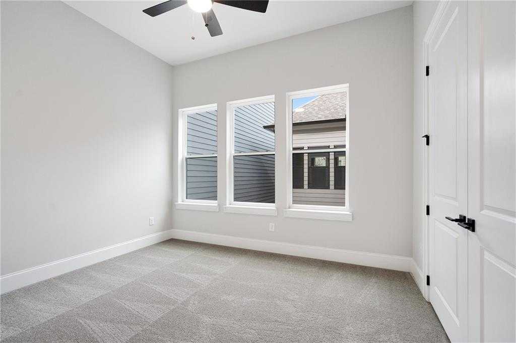 Bright bedroom with gray walls, ceiling fan, large triple windows, and carpet in Davidson Homes The Seaside B, Woodstock, GA