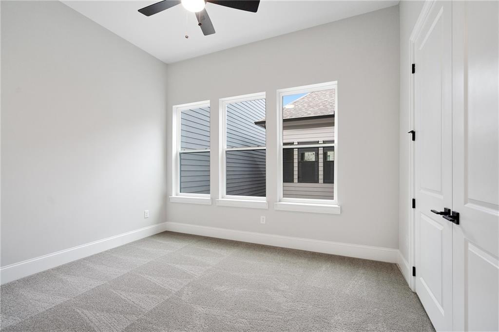 Bright bedroom with gray walls, ceiling fan, large triple windows, and carpet in Davidson Homes The Seaside B, Woodstock, GA