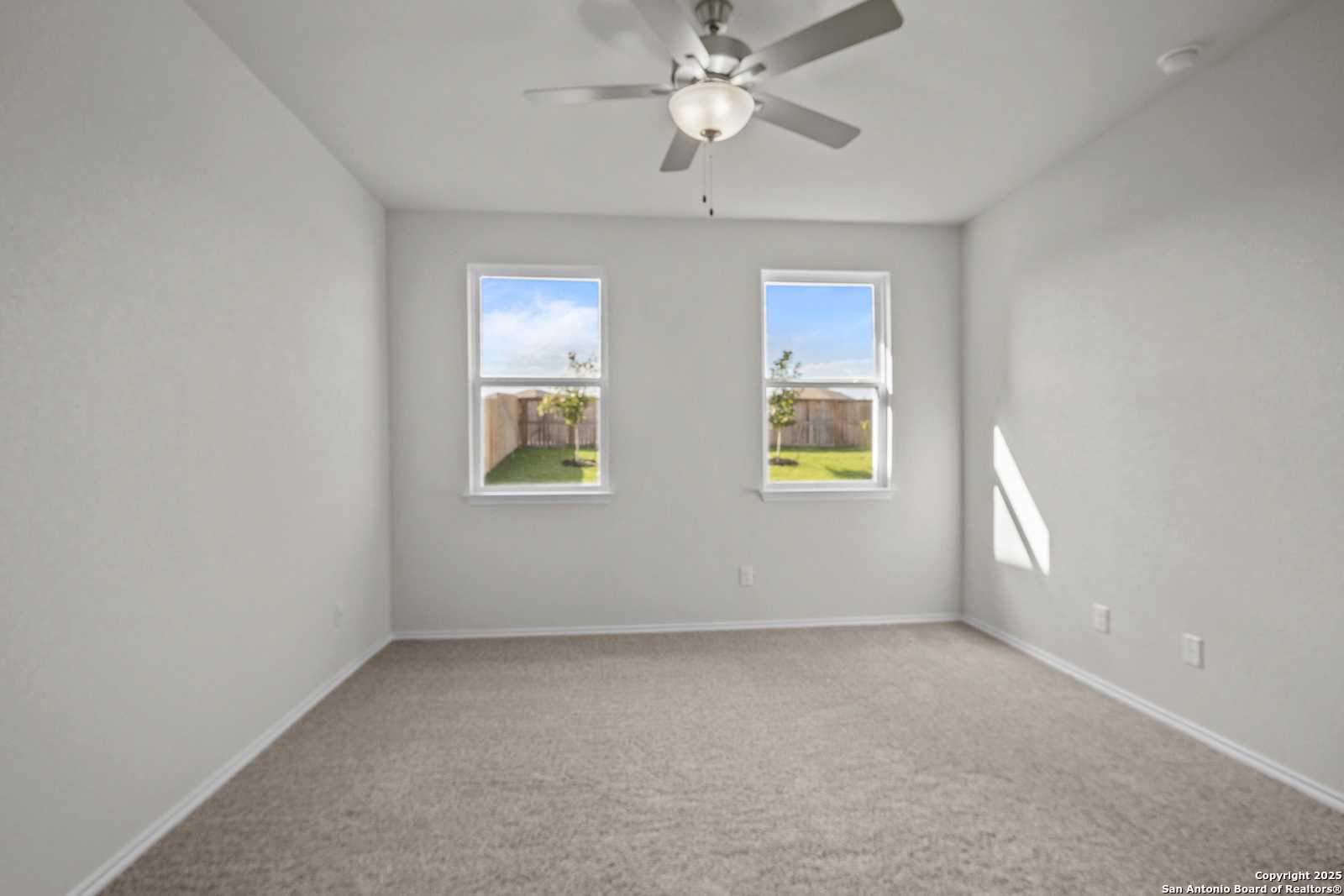 Bright secondary bedroom with ceiling fan, large windows to lush backyard, carpeted floor in Davidson Homes The Asheville J, San Antonio