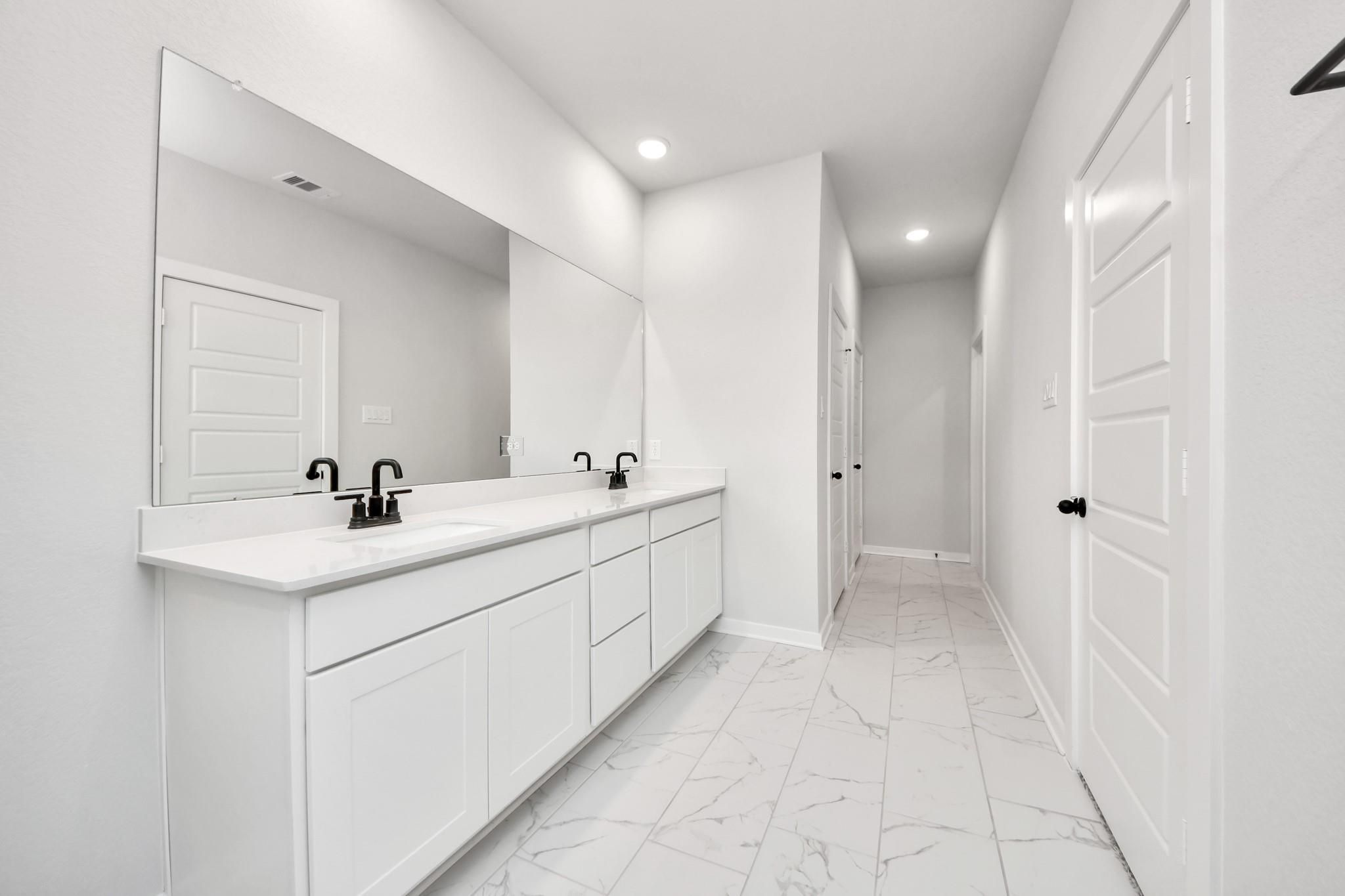 Modern primary bathroom with double vanity, white cabinets, and matte black fixtures in The Sorrento E at Sundance Cove.