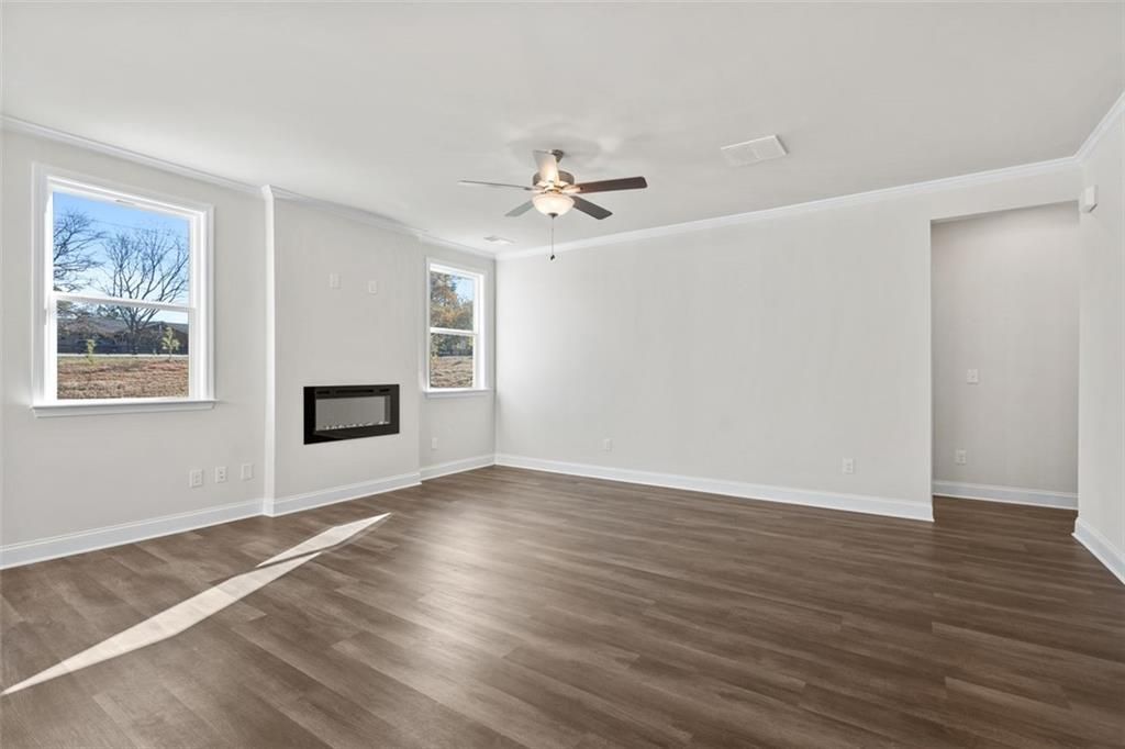 Spacious living room with modern linear fireplace, hardwood floors, and large windows in Davidson Homes The Ash C at Wehunt Meadows, Hoschton