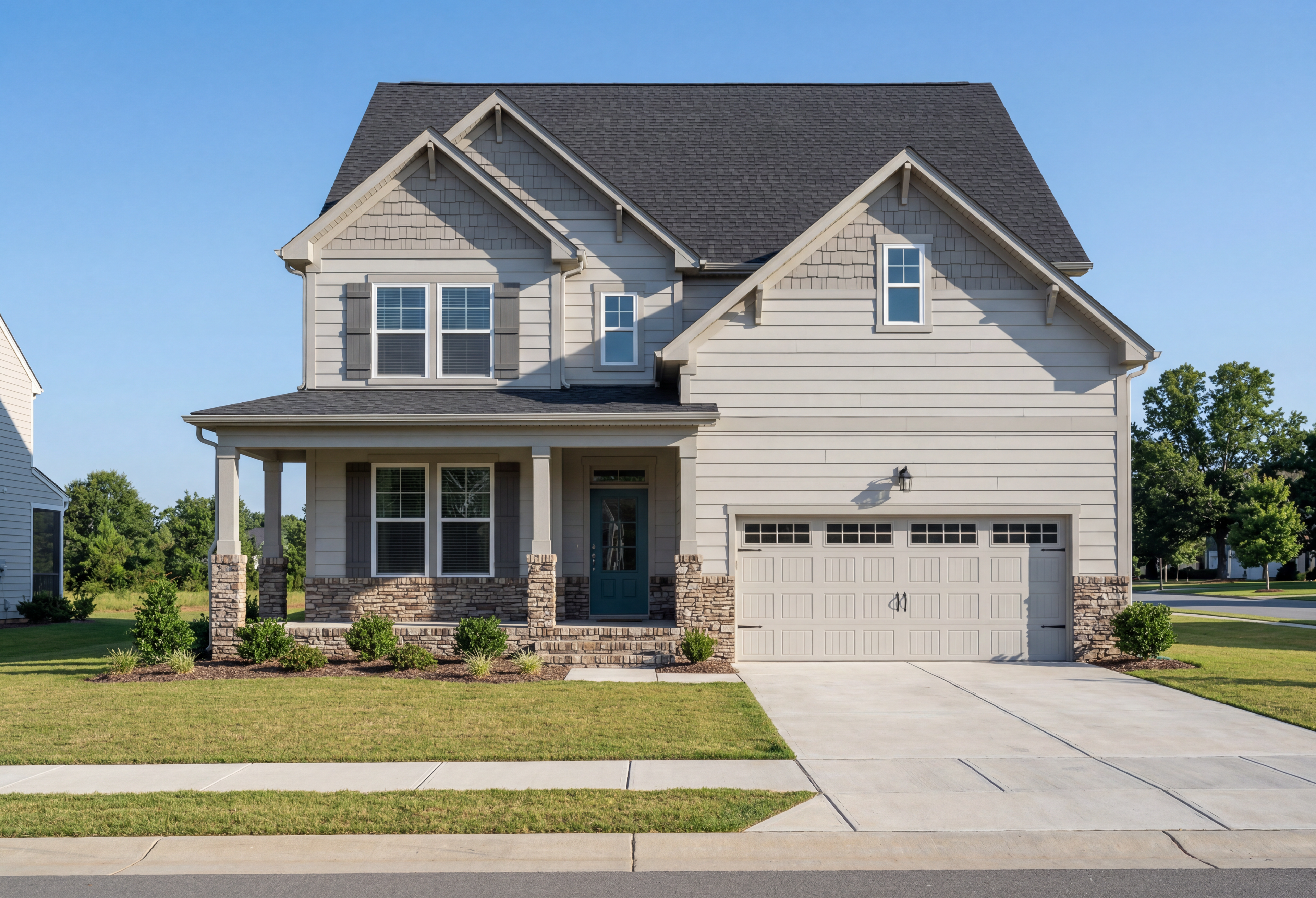 Two-story The Hickory II home with stone and vinyl exterior, covered porch, 2-car garage, and manicured lawn in Holly Springs NC