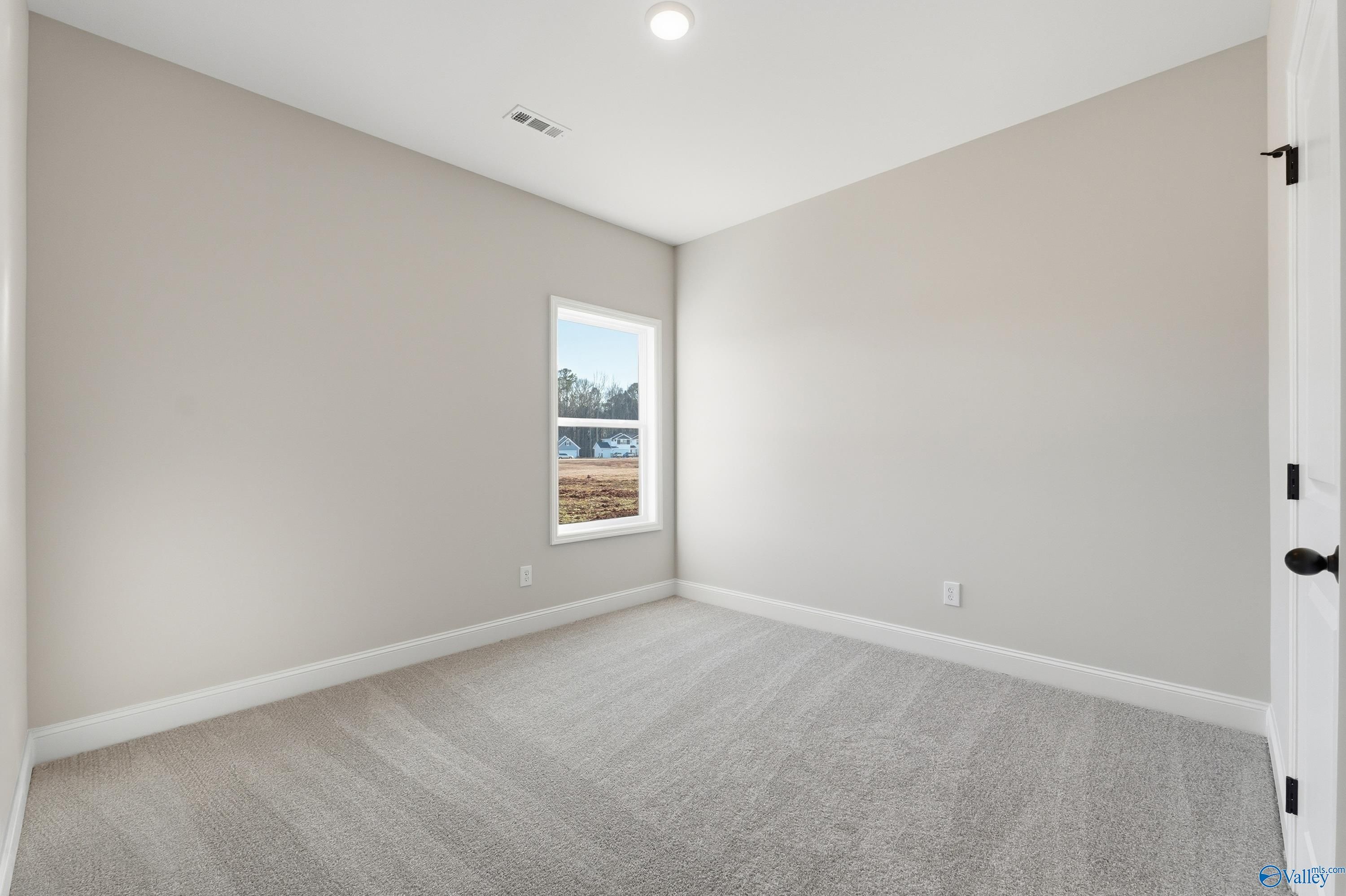 Bright secondary bedroom with beige walls, large window, plush carpet in Davidson Homes The Franklin E, Hazel Green, Alabama