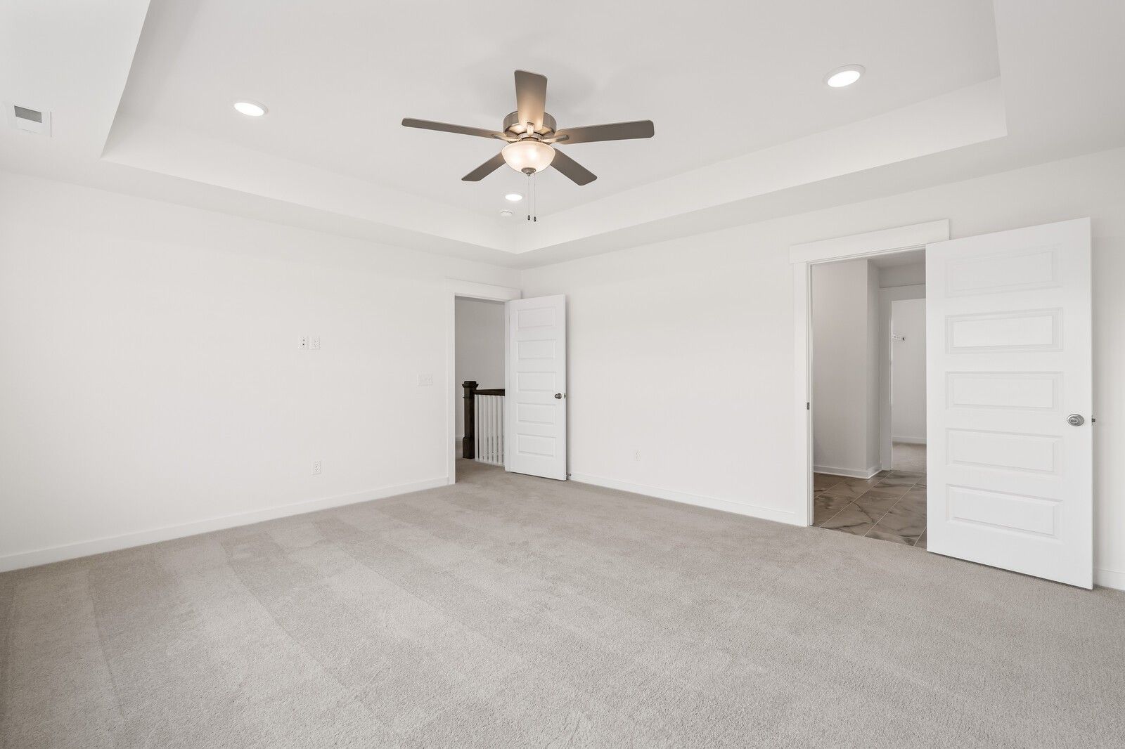 Spacious primary bedroom with tray ceiling and carpet flooring in The Willow D floor plan at Benders Cove, Mt. Juliet.