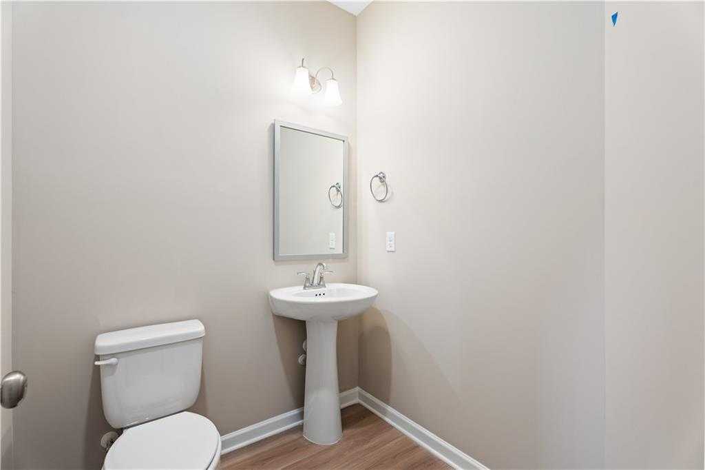 Elegant powder room with pedestal sink, frameless mirror, and white toilet in Davidson Homes The Bartlett, Phenix City, AL