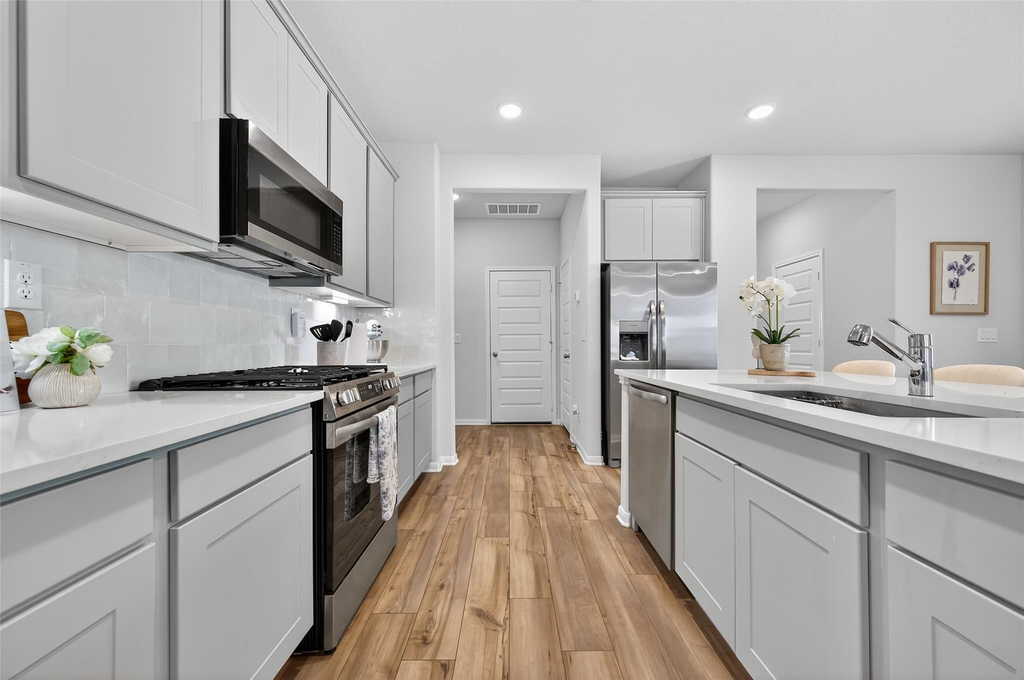 Modern white shaker kitchen with stainless steel appliances, quartz counters, subway tile in Davidson Homes The Brazos E, Magnolia TX