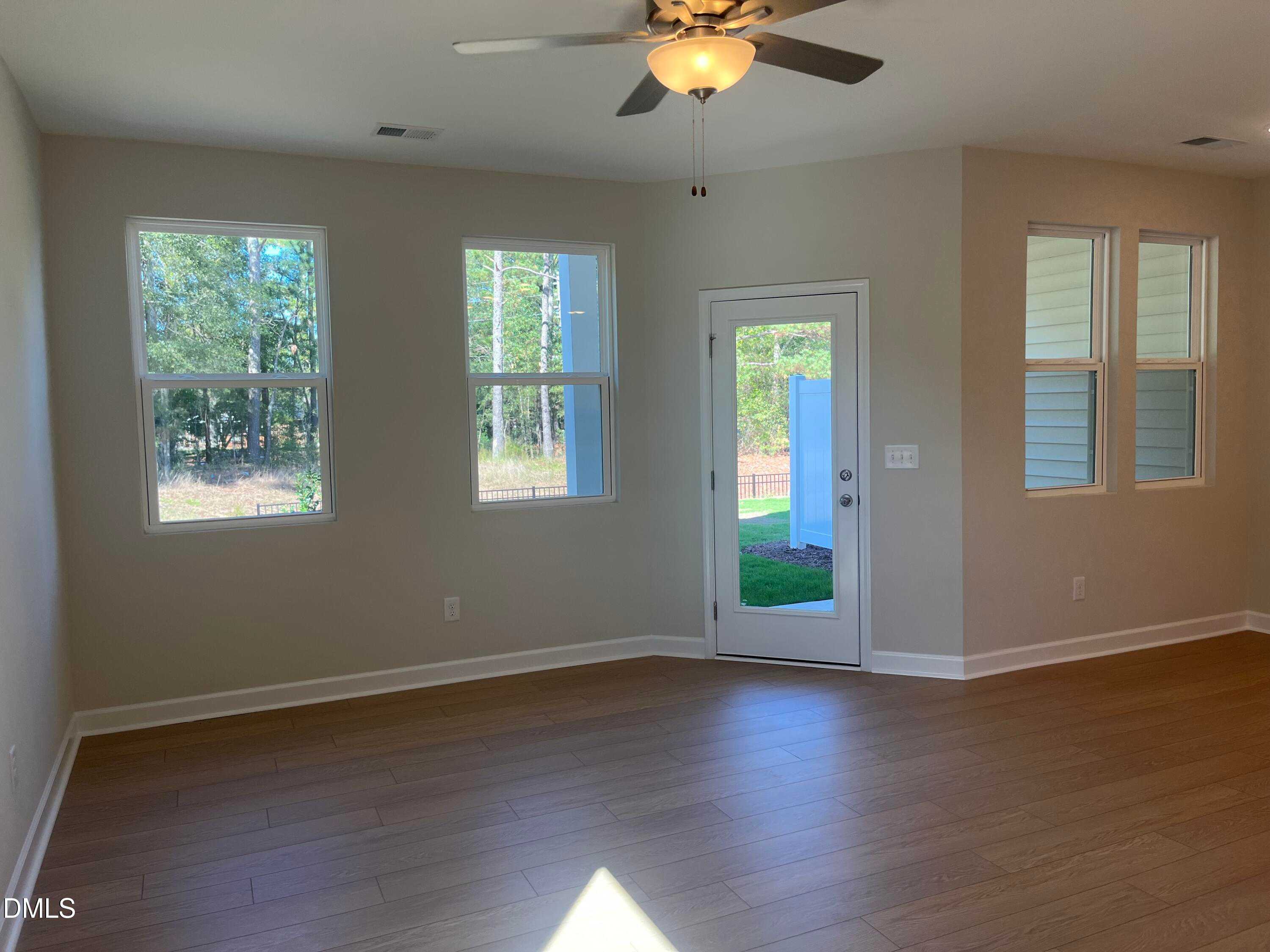 Bright living room with hardwood floors, large windows to wooded backyard, ceiling fan in Davidson Homes The Graham, Fuquay-Varina