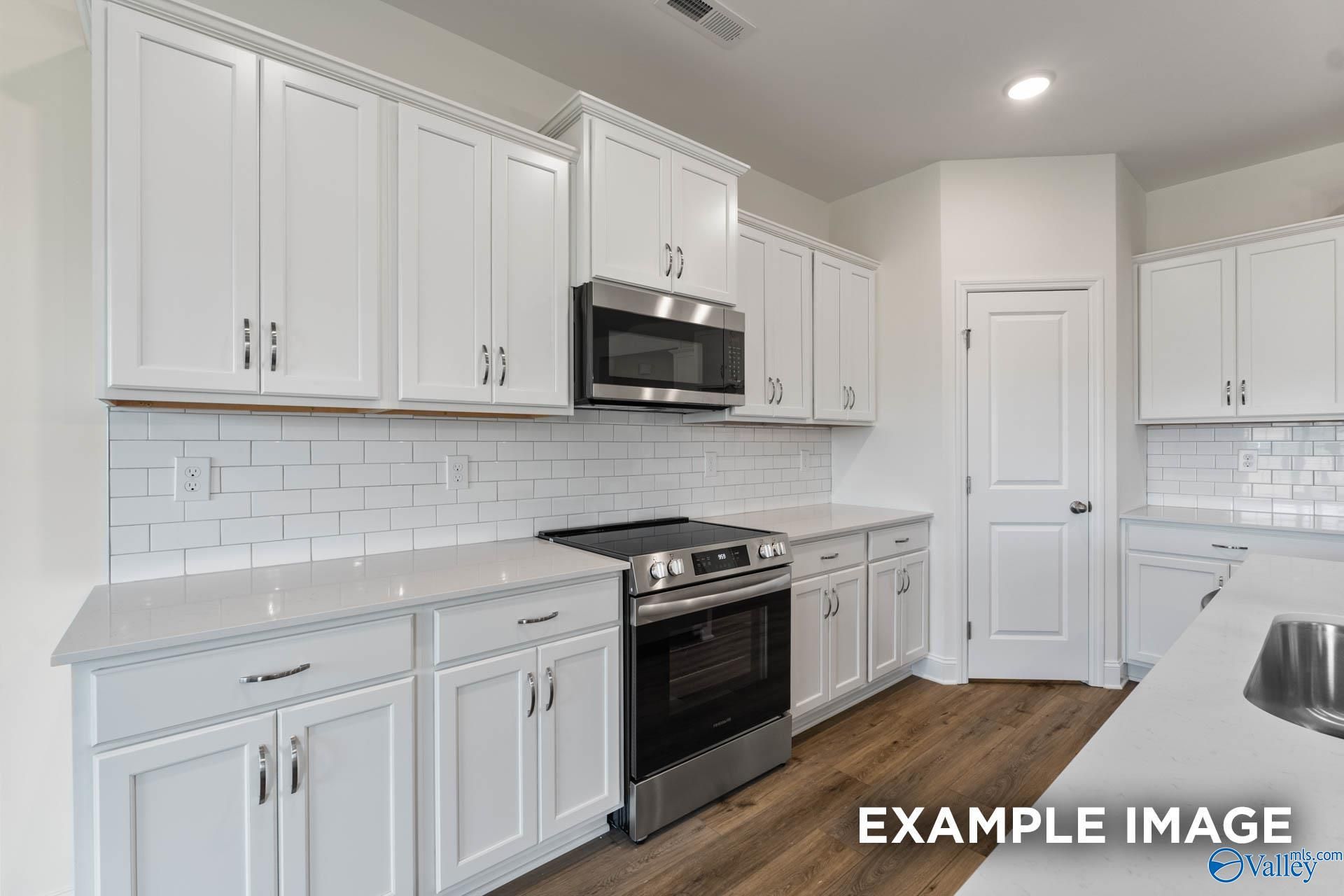 Modern white kitchen with stainless appliances, quartz counters, subway tile backsplash in Davidson Homes The Harrison C, Athens AL
