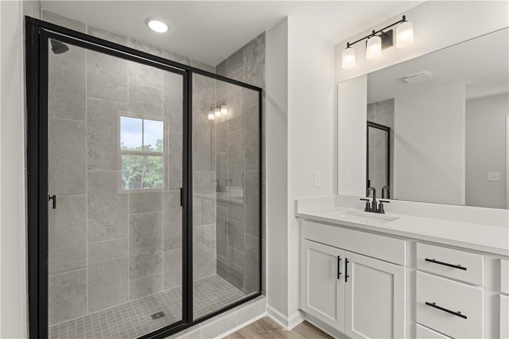 Modern bathroom with tiled walk-in shower and white vanity in The Hartwell A plan at The Bluffs, Canton, Georgia.