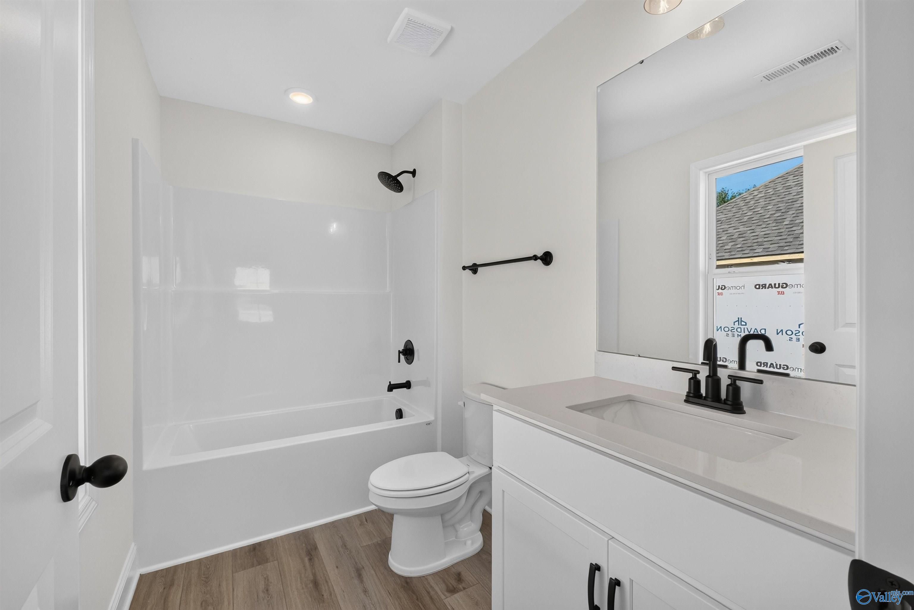 Modern bathroom with white vanity, matte black fixtures, and tub-shower combo in Davidson Homes The Ashport L, New Market, Alabama