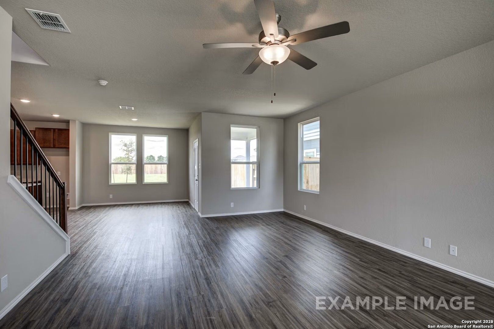Spacious open living area with hardwood floors, ceiling fan, and large windows in Davidson Homes The Murray K, San Antonio, Texas