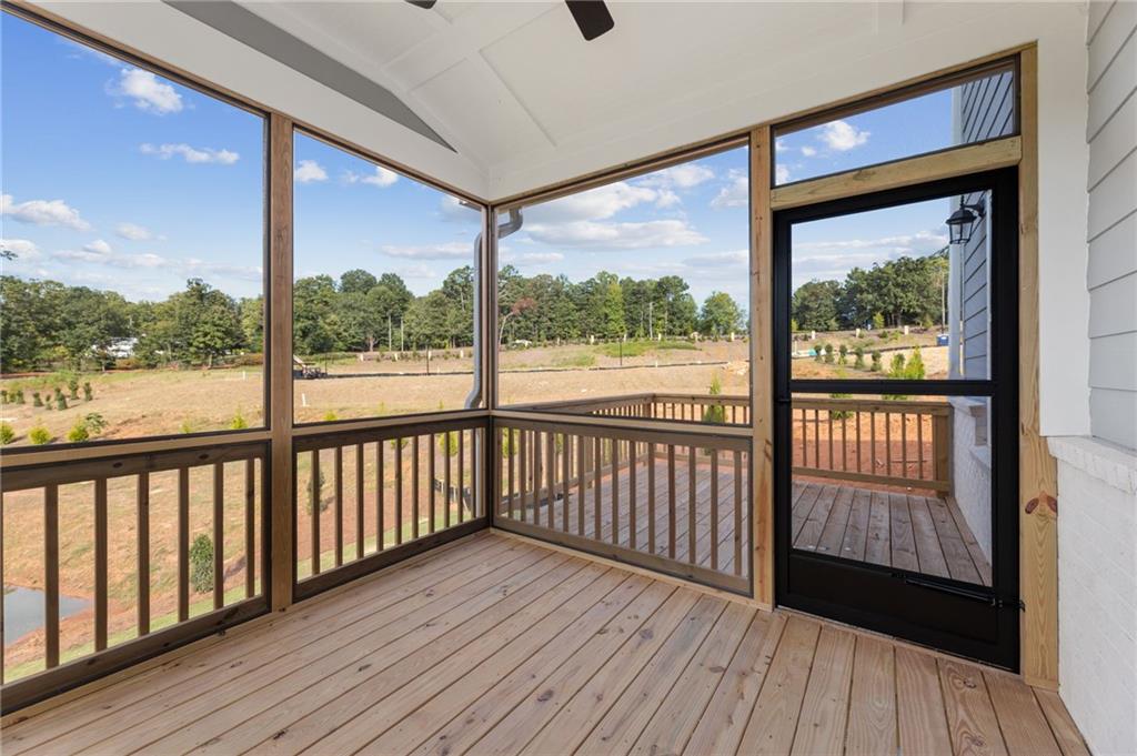 Screened porch with wooden deck, ceiling fan, and wooded backyard view in Davidson Homes The Hampton C, Buford, Georgia