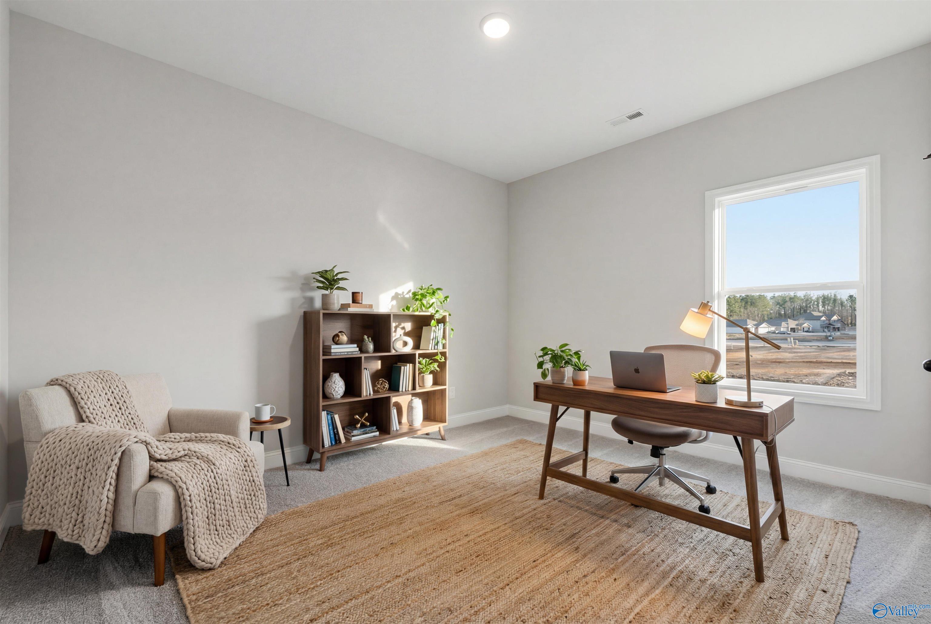 Cozy home office with wooden desk, bookshelf, plants, armchair, and window view in Davidson Homes The Daphne D, Arab, Alabama