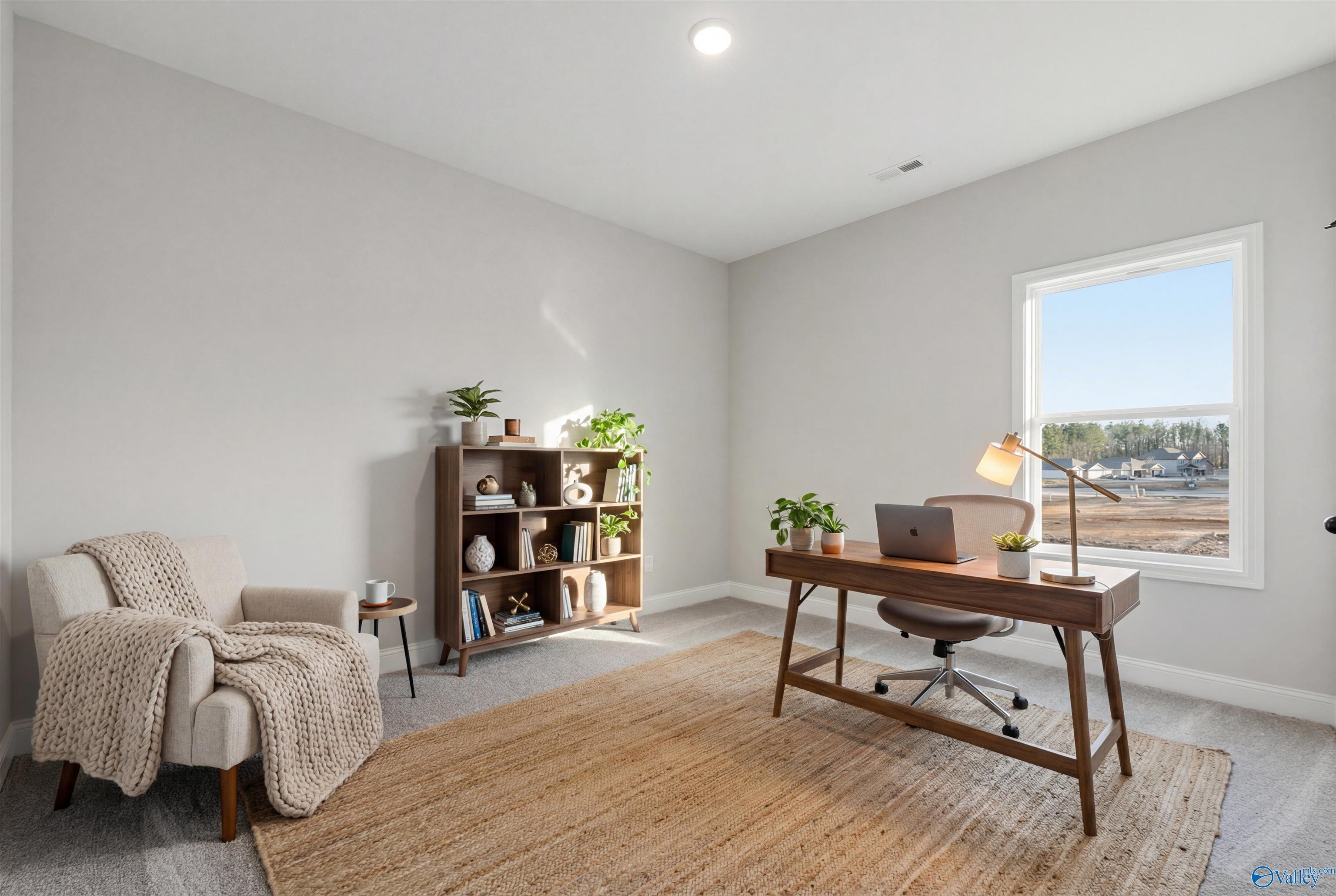 Cozy home office with wooden desk, bookshelf, plants, armchair, and window view in Davidson Homes The Daphne D, Arab, Alabama
