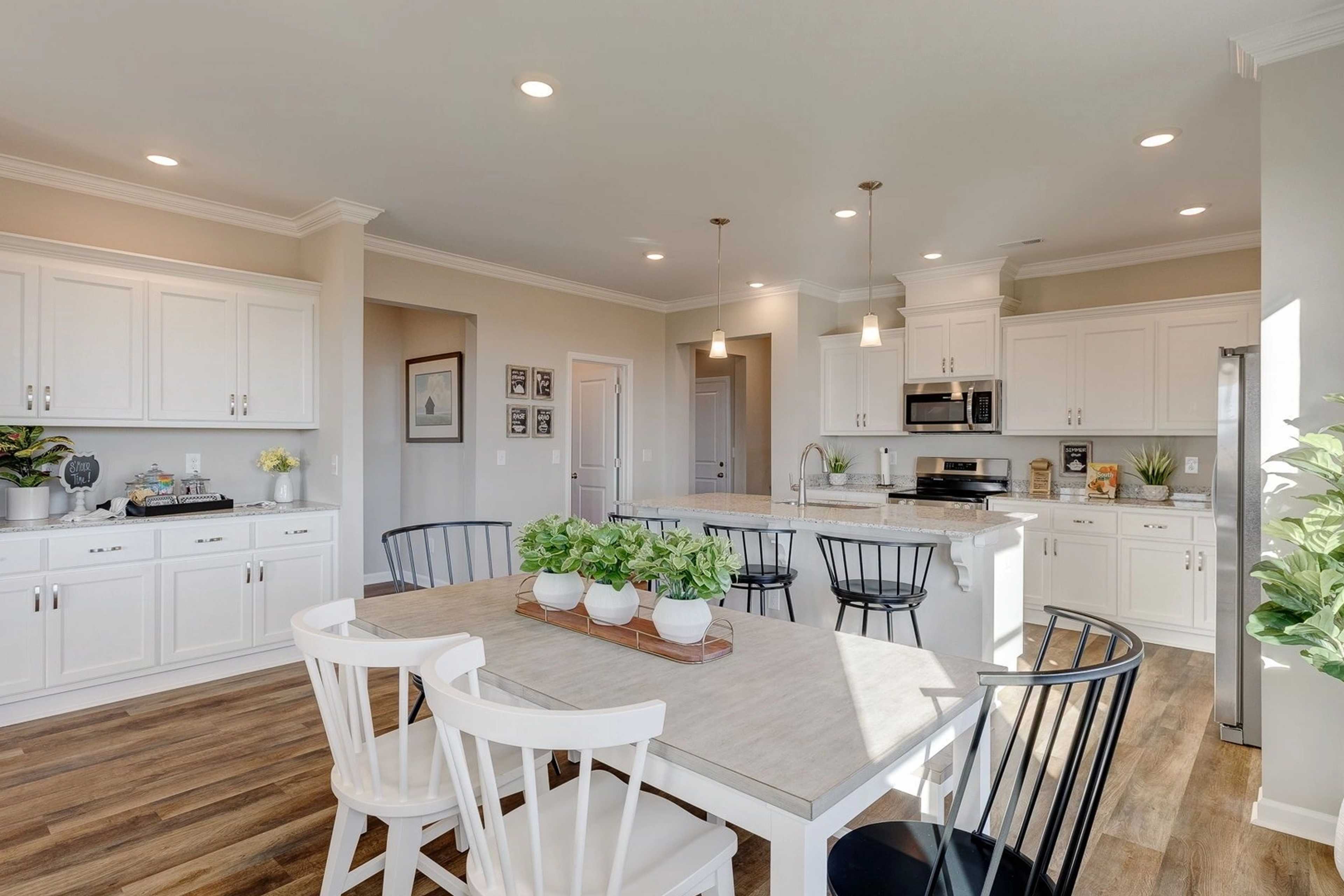Spacious open-concept kitchen and dining area in Carroll Green, Harvest AL with white cabinets, large island, hardwood floors