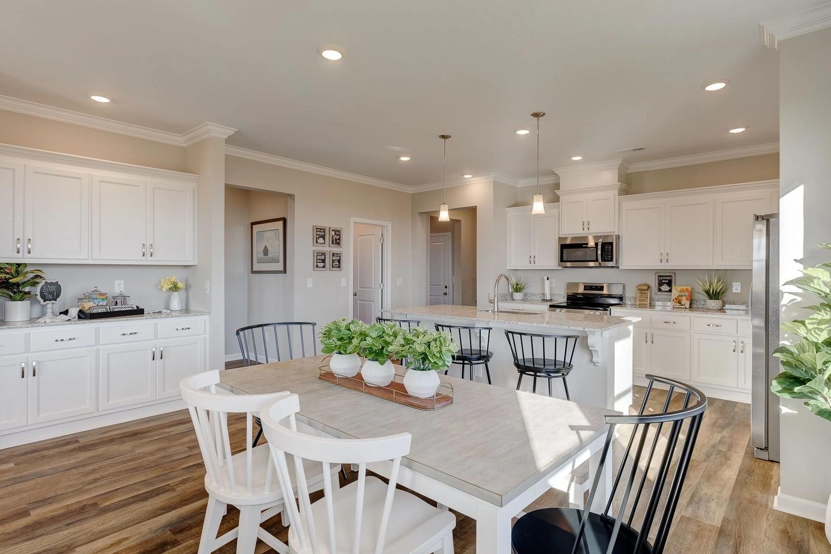 Spacious open-concept kitchen and dining area in Carroll Green, Harvest AL with white cabinets, large island, hardwood floors