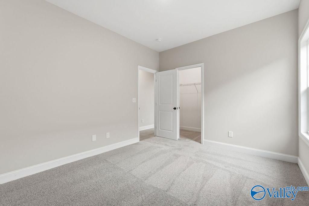 Spacious master bedroom with walk-in closet, large window, and neutral walls in Davidson Homes The Rockford B, Hartselle, Alabama