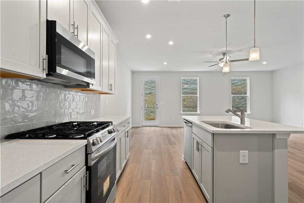 Modern kitchen with white shaker cabinets, stainless appliances, subway tile backsplash, and island sink in Davidson Homes The Marion B, Kennesaw, GA