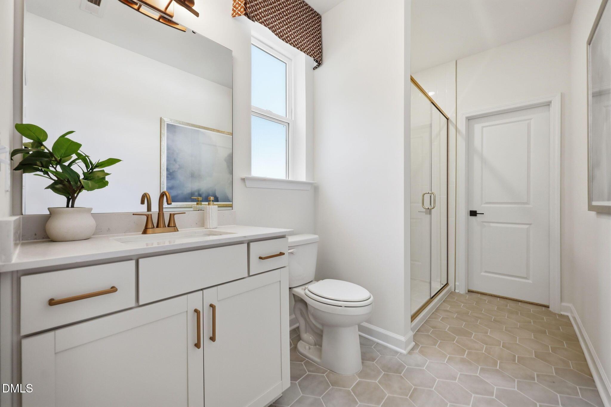 Modern bathroom with vanity, gold fixtures, and glass shower in The Aspen B floor plan at Wendell Ridge, North Carolina.