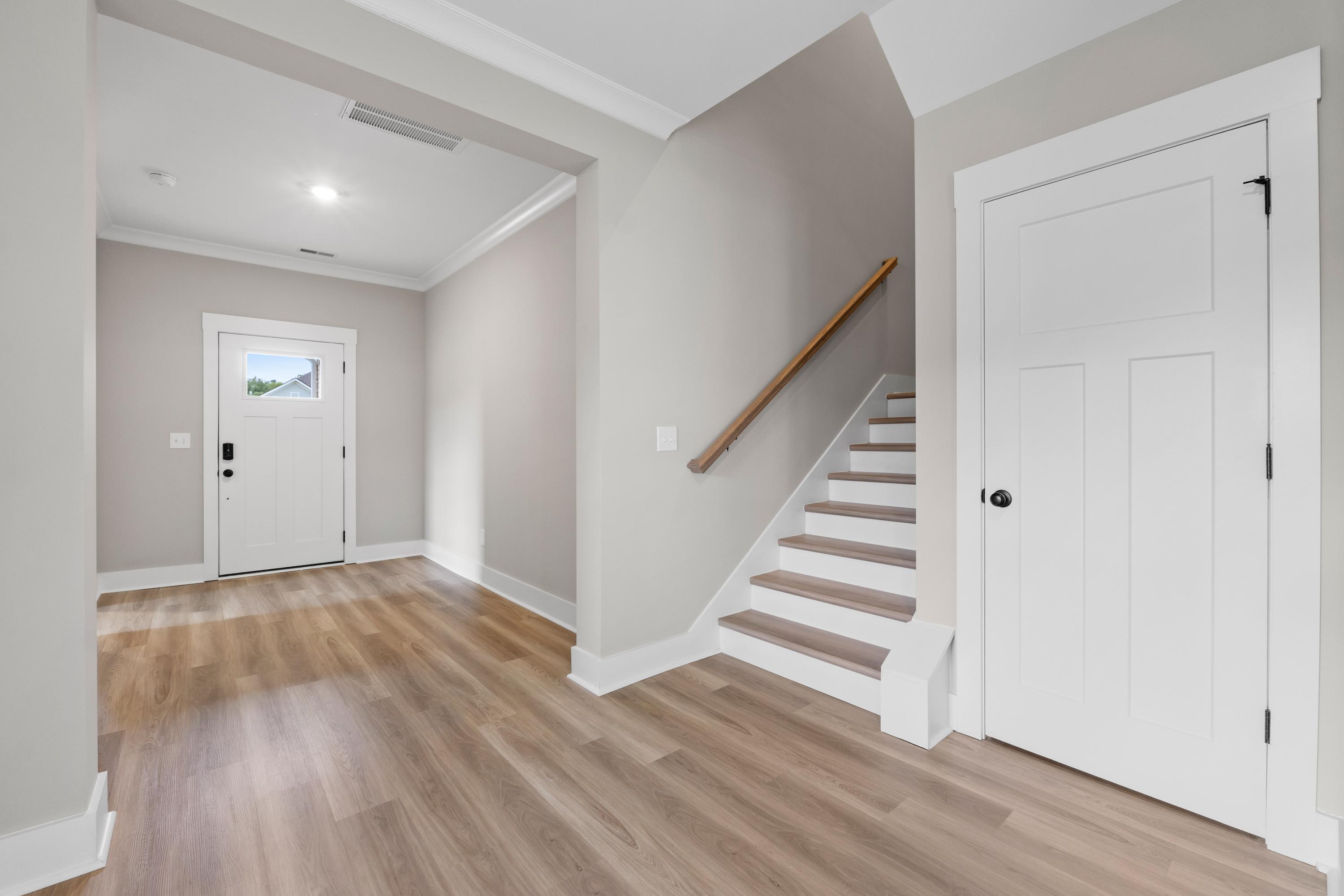 Spacious foyer in The Oxford B featuring light oak hardwood floors, gray walls, white doors, and open staircase