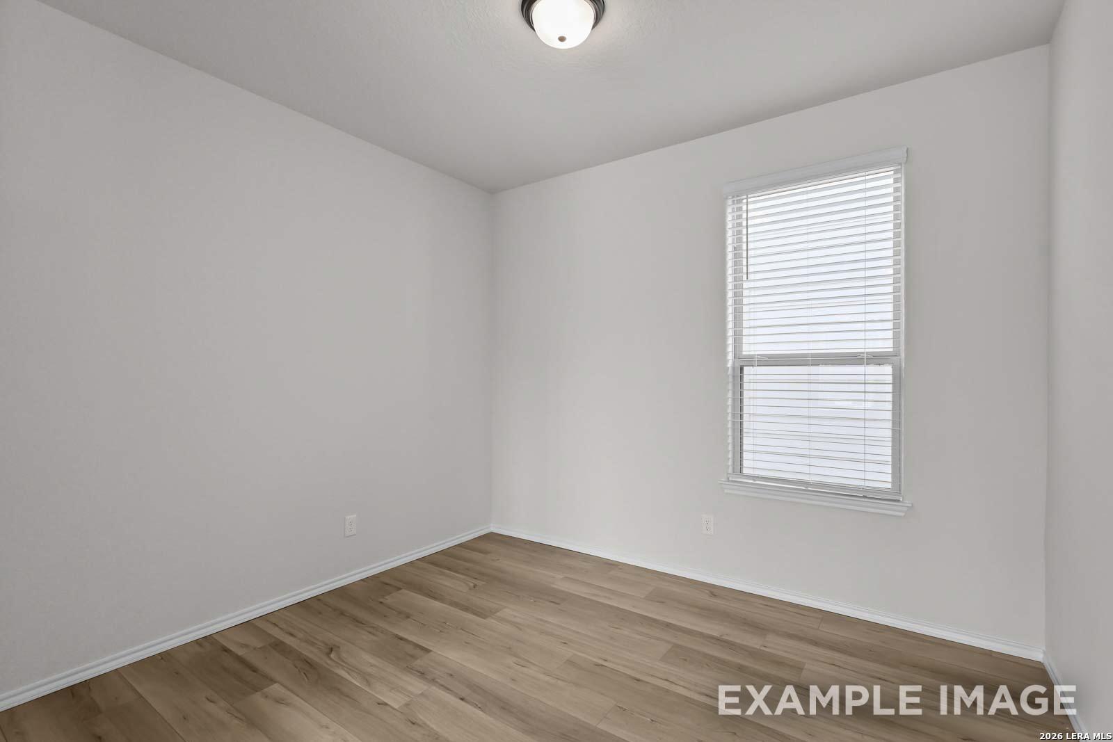 Bright neutral bedroom with wood-look flooring and blinds in The Florence D floor plan by Davidson Homes, San Antonio.