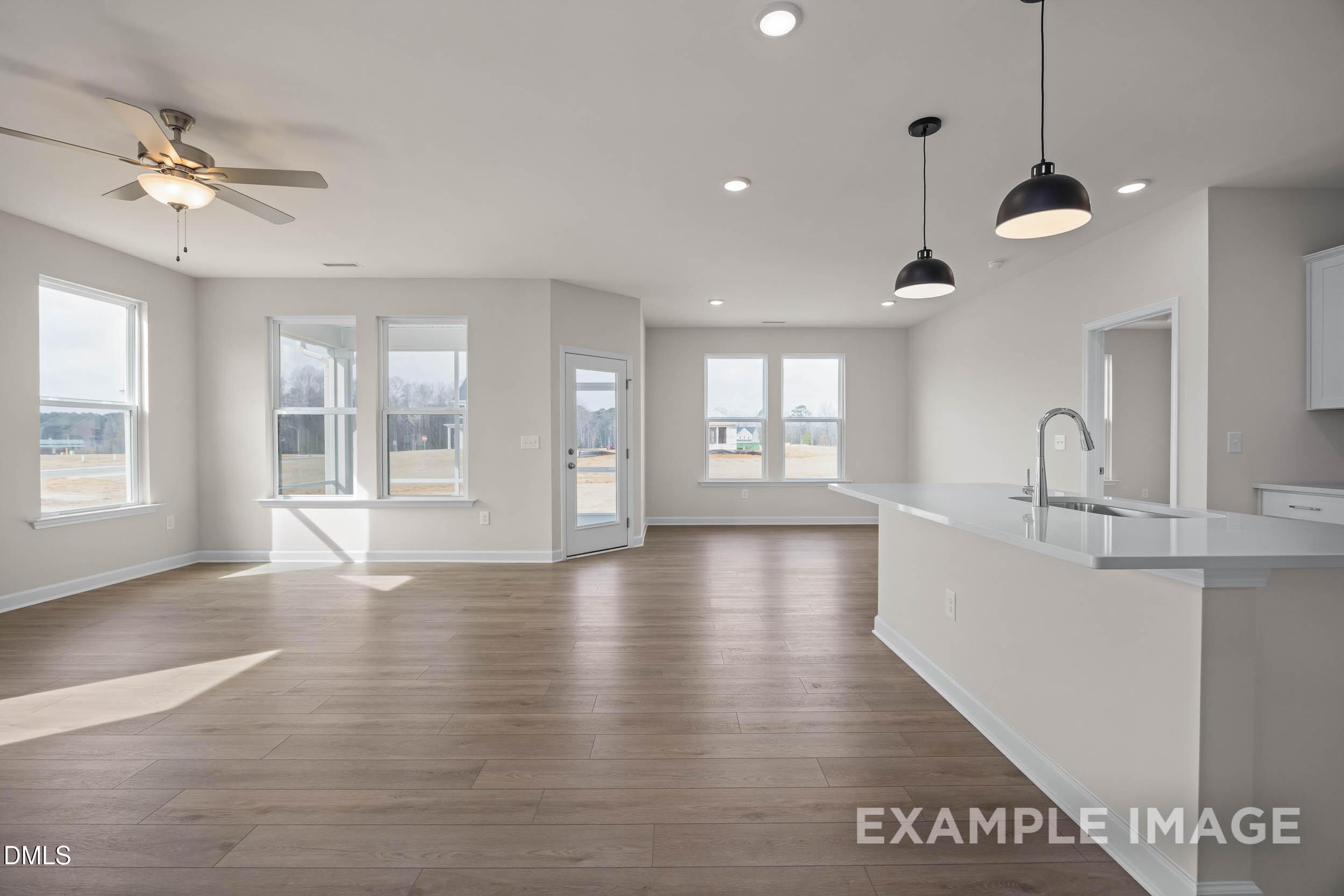 Open-concept kitchen and living area with hardwood floors in The Franklin C floor plan at Retreat at North Main, Lillington.