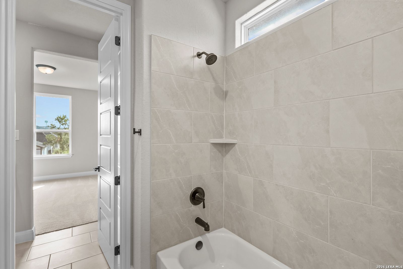 Tiled tub shower combo with oil-rubbed bronze fixtures in Davidson Homes Foster E bathroom, Castroville TX