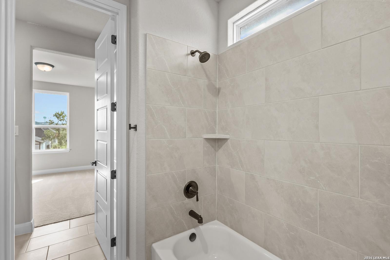 Tiled tub shower combo with oil-rubbed bronze fixtures in Davidson Homes Foster E bathroom, Castroville TX