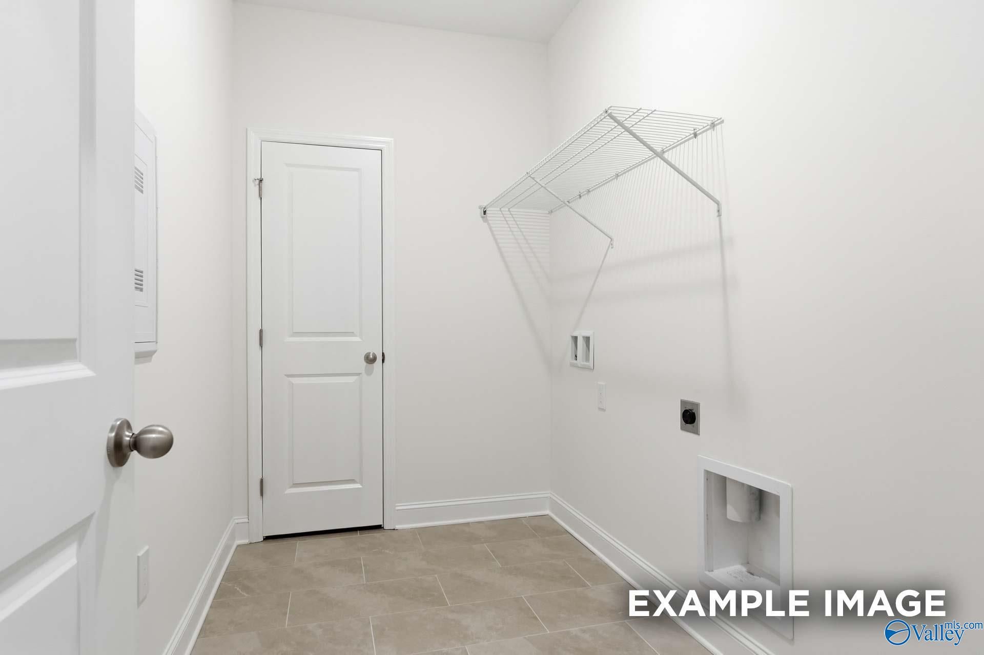 Laundry room with white walls, tiled floor, and wire shelving in The Valencia floor plan by Davidson Homes, Meridianville.