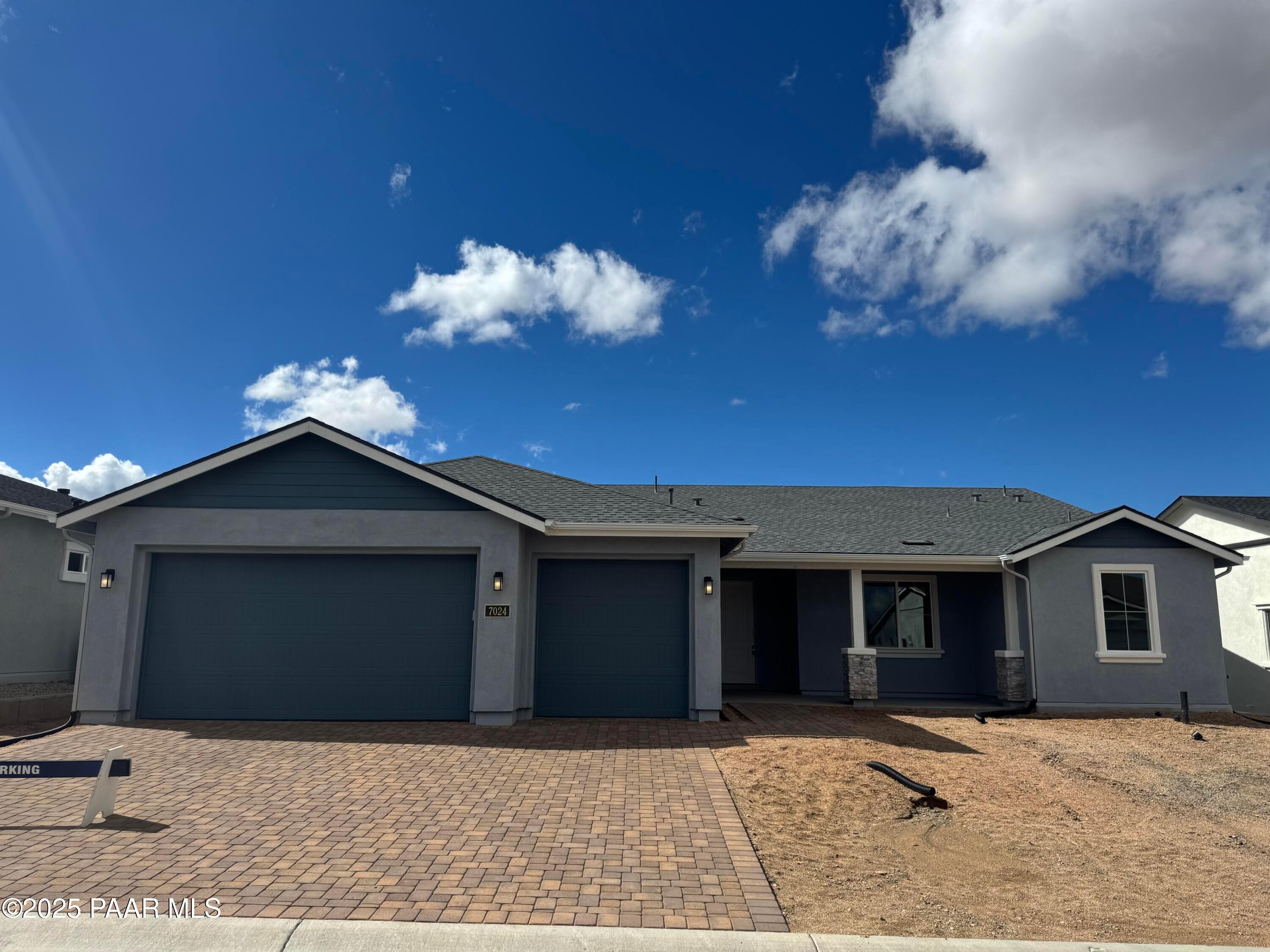 Modern gray single-story home with 3-car garage, brick paver driveway, and stone accents in Westwood, Prescott, Arizona by Davidson Homes